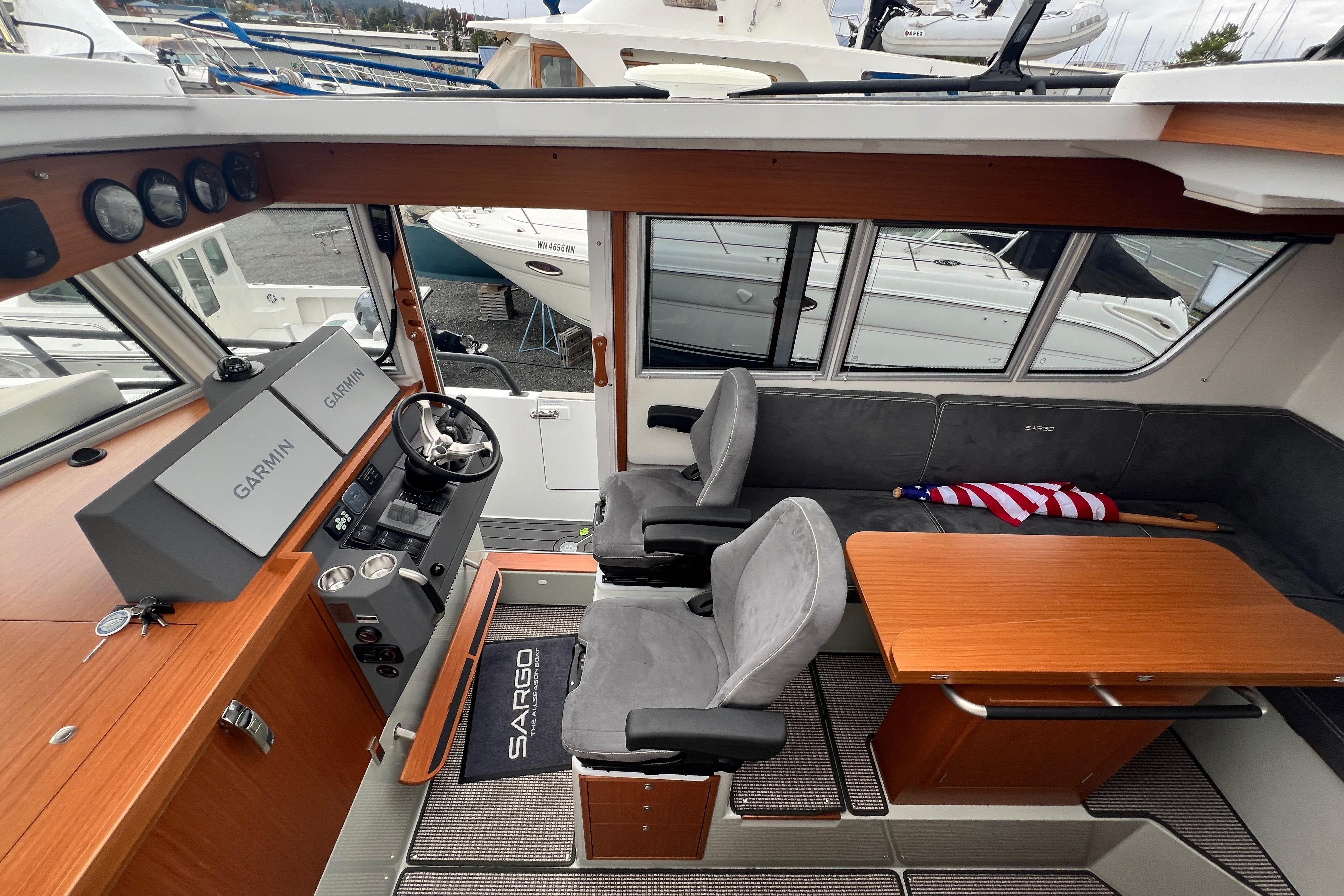Interior of 2024 Sargo 36 Explorer boat with helm, seating, and wooden table.