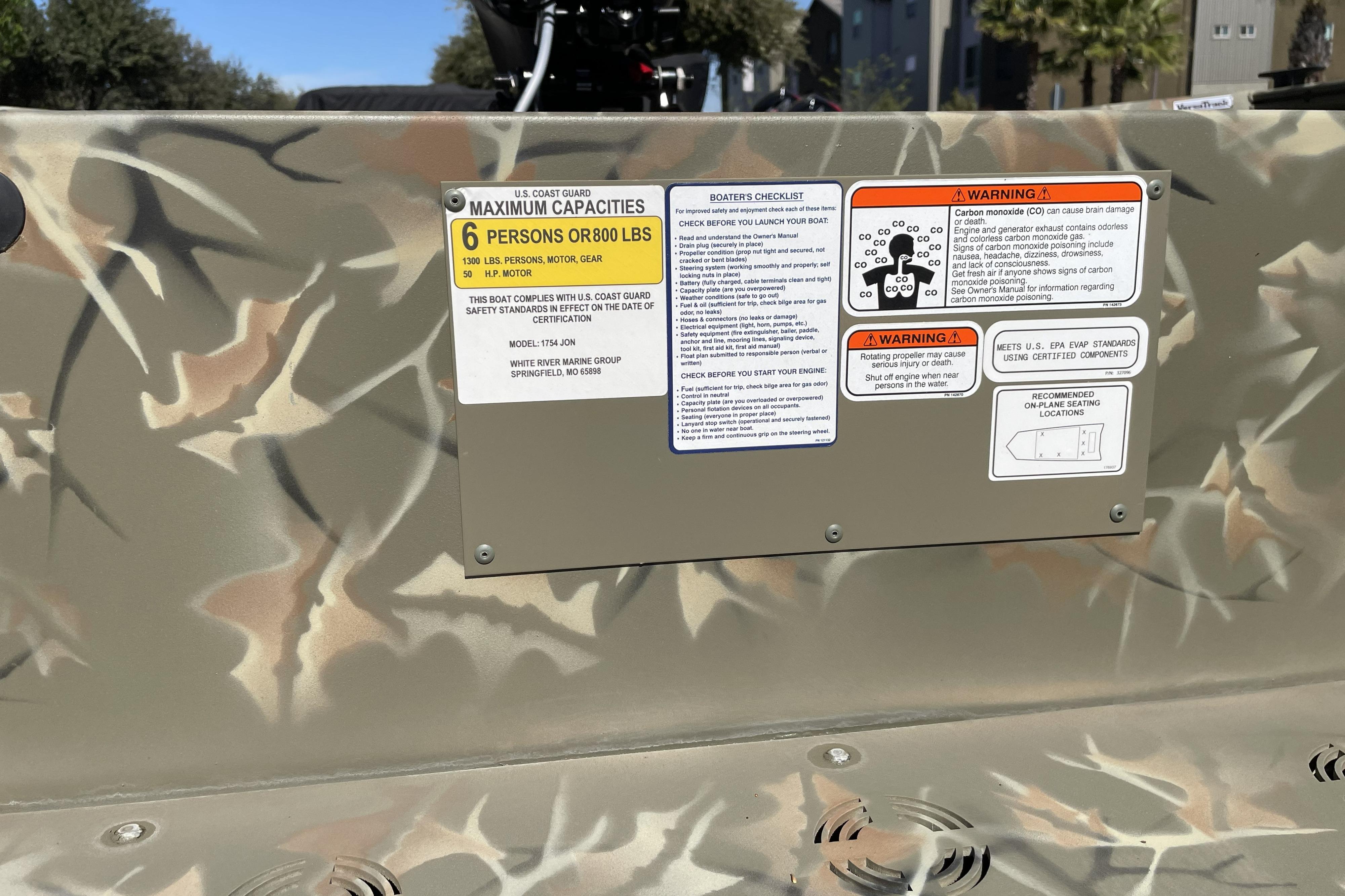 2025 Tracker Grizzly 1754 Jon boat capacity and safety warning labels on camouflage surface.
