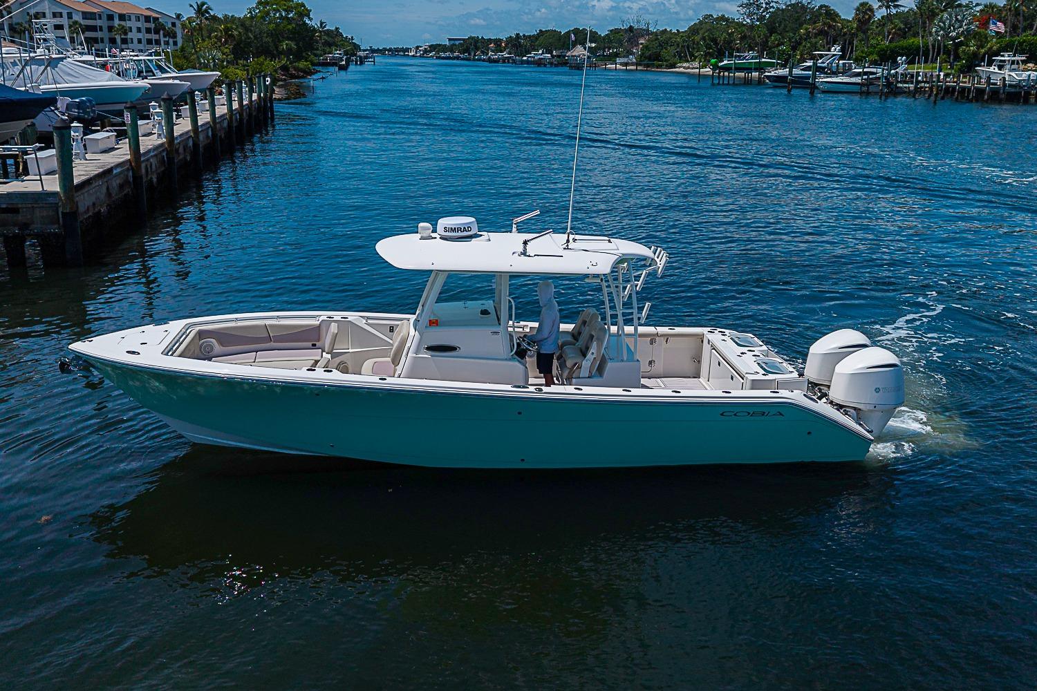2019 Cobia 320 Center Console boat cruising on a scenic waterway.