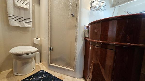 Luxurious bathroom in 2005 Neptunus 56 Flybridge yacht with shower and wooden cabinetry.