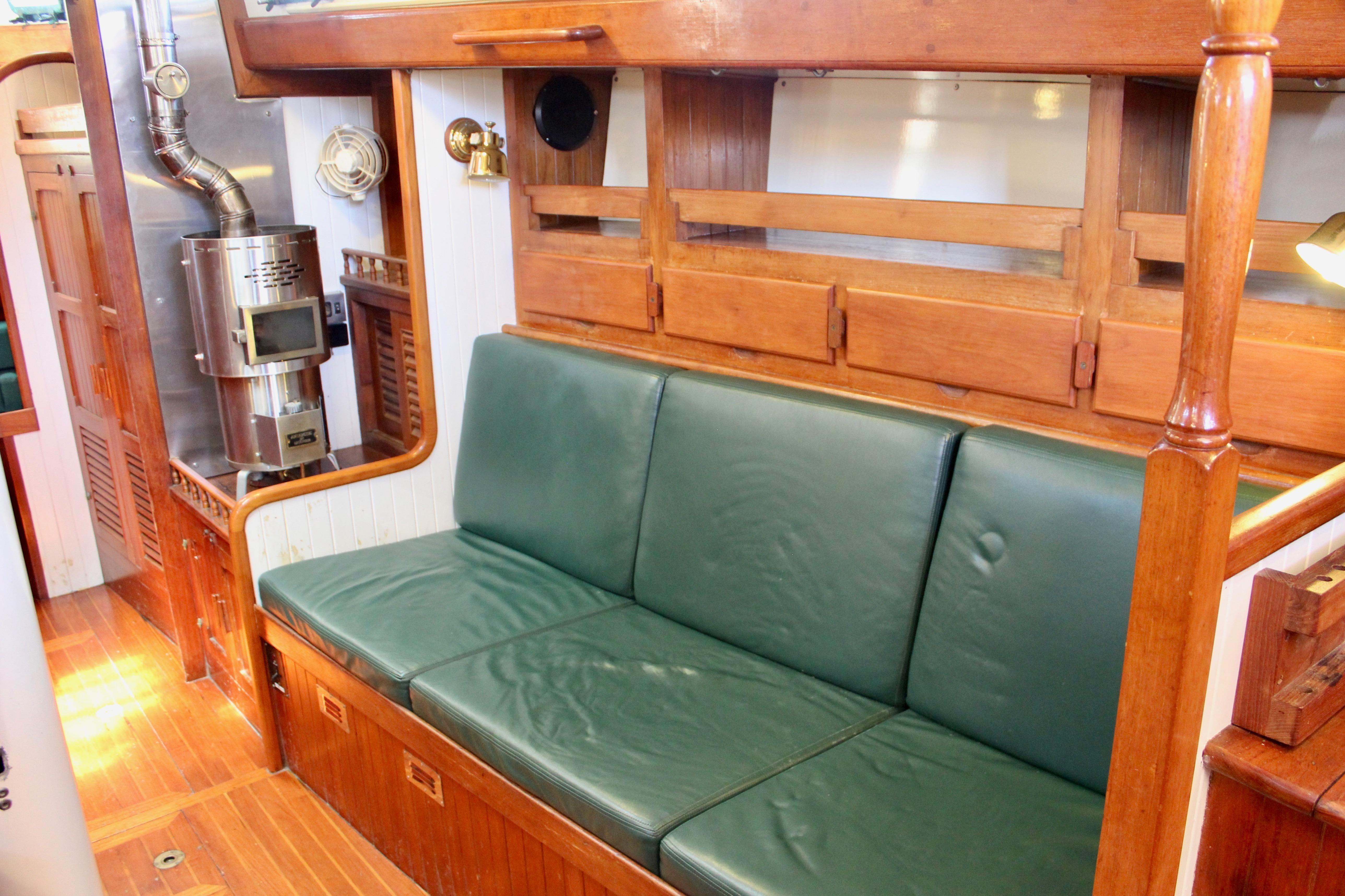 Interior of 1981 Kelly Peterson 46 yacht with green leather seating and wood paneling.