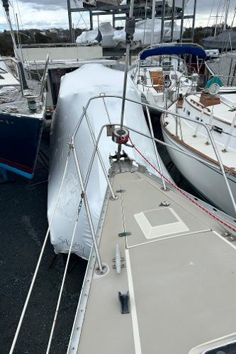 1983 O'Day 39 sailboat docked, covered in white tarp, surrounded by other boats.