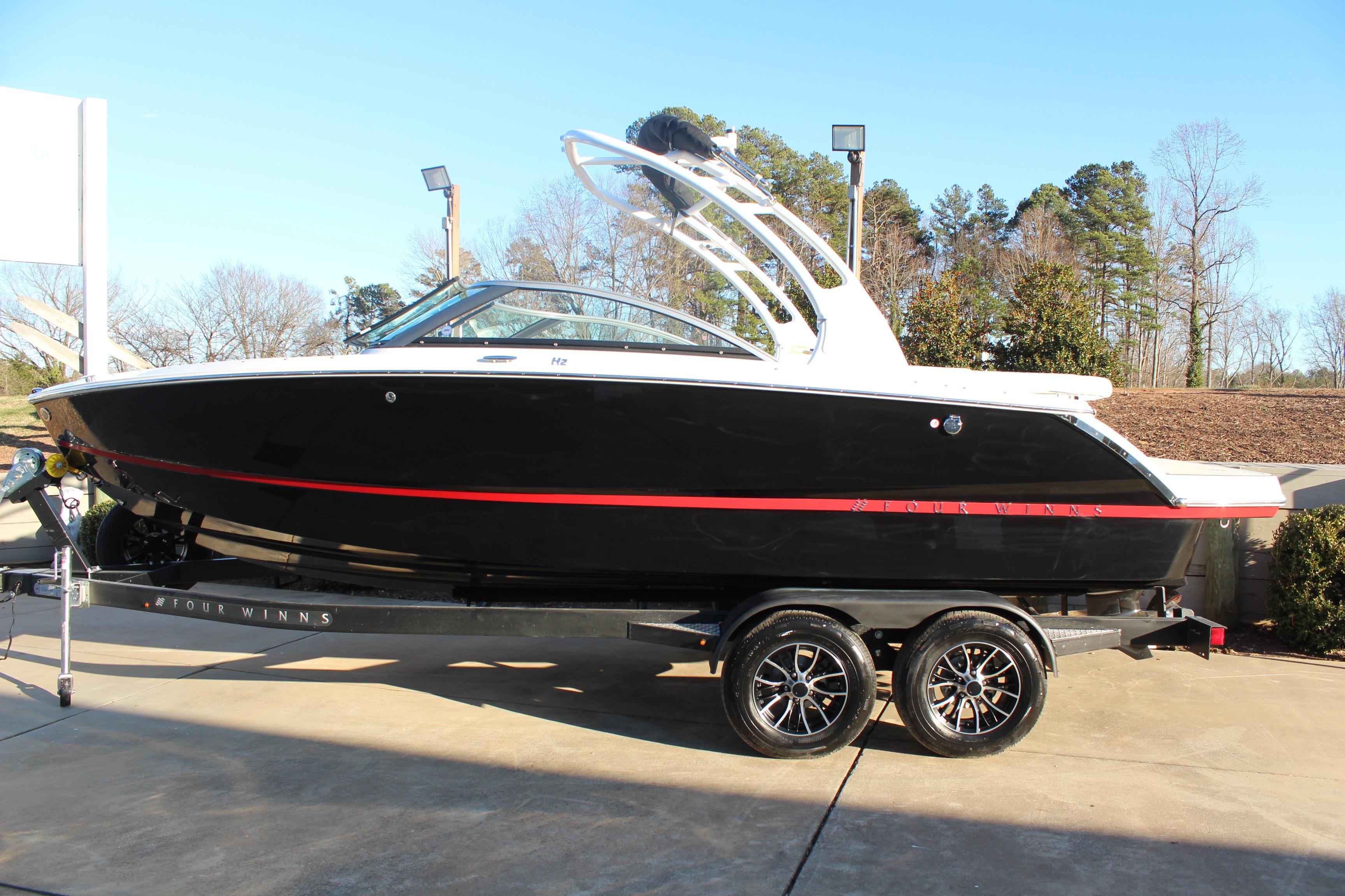 2026 Four Winns H2 Freedom boat on trailer, black with red accents, parked outdoors.
