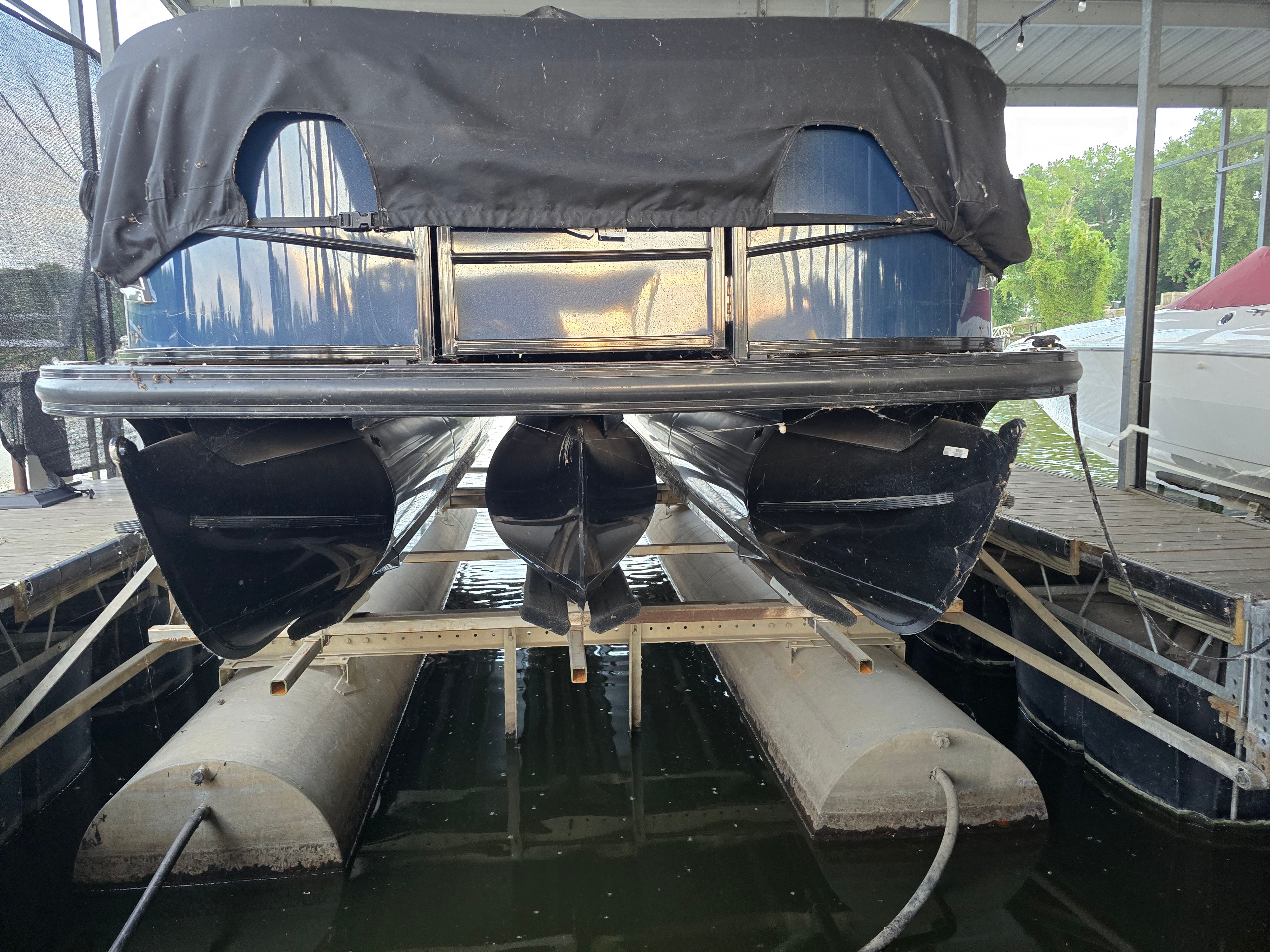 A 2021 Regency 230 LE3 pontoon boat is docked under a covered area.