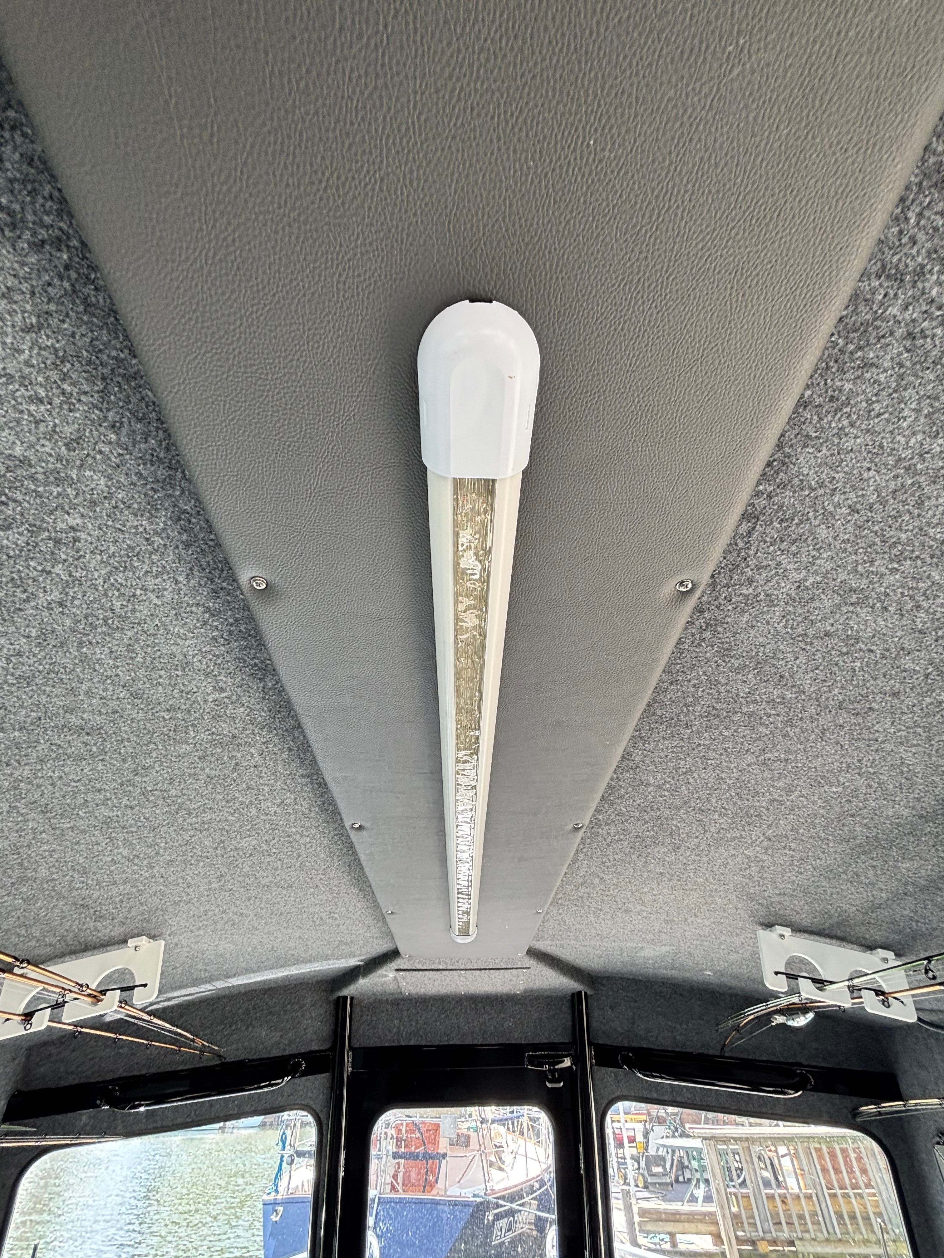 Interior of a boat with a gray headliner and a long ceiling light.