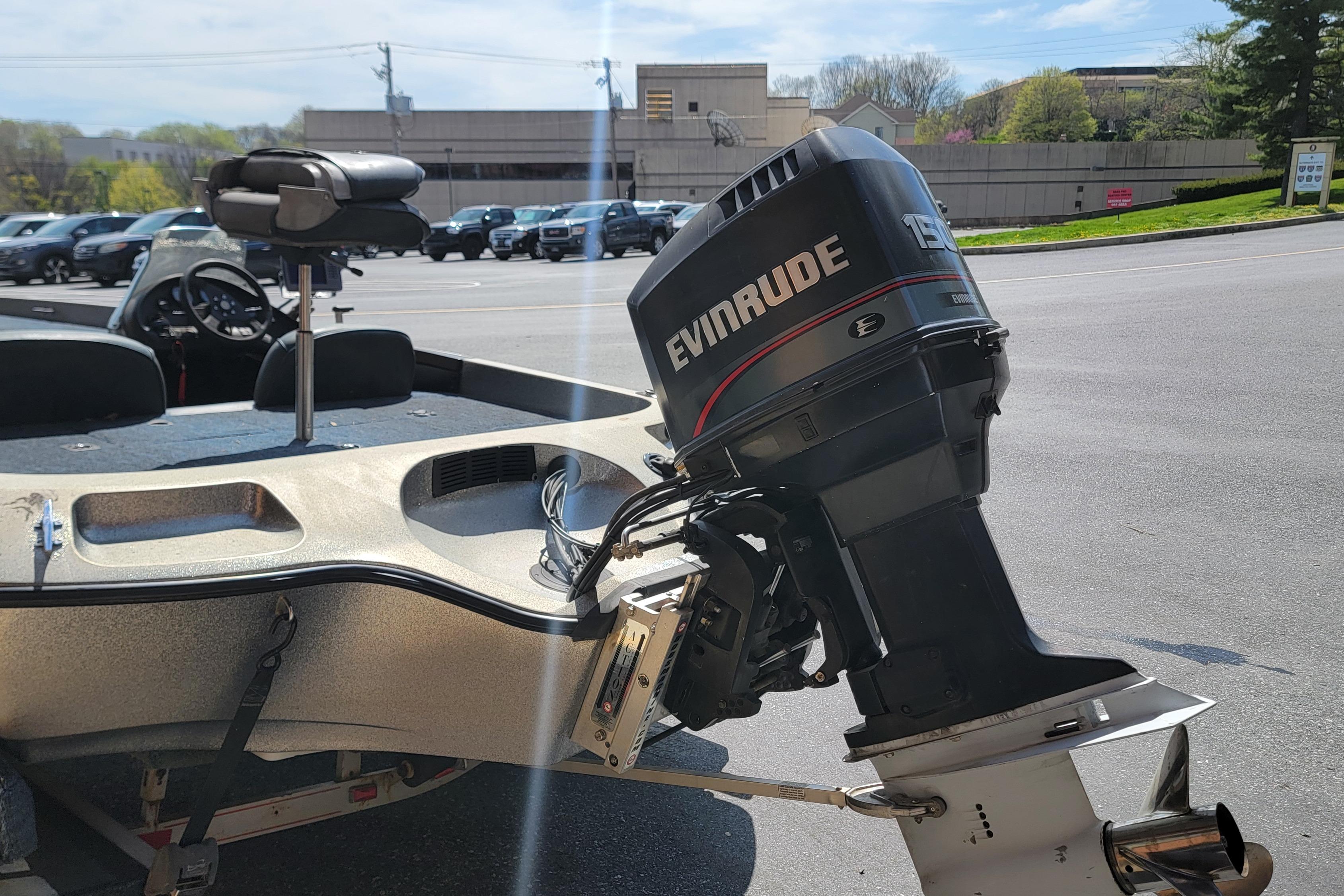 1995 Ranger boat with Evinrude 150 outboard motor in parking lot.