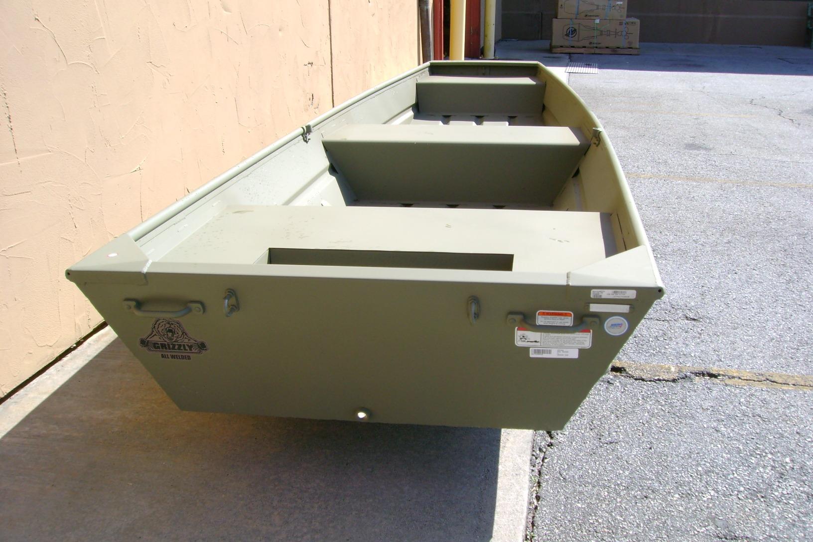 2026 Tracker Grizzly 14 Jon boat in olive green, parked outdoors on concrete.