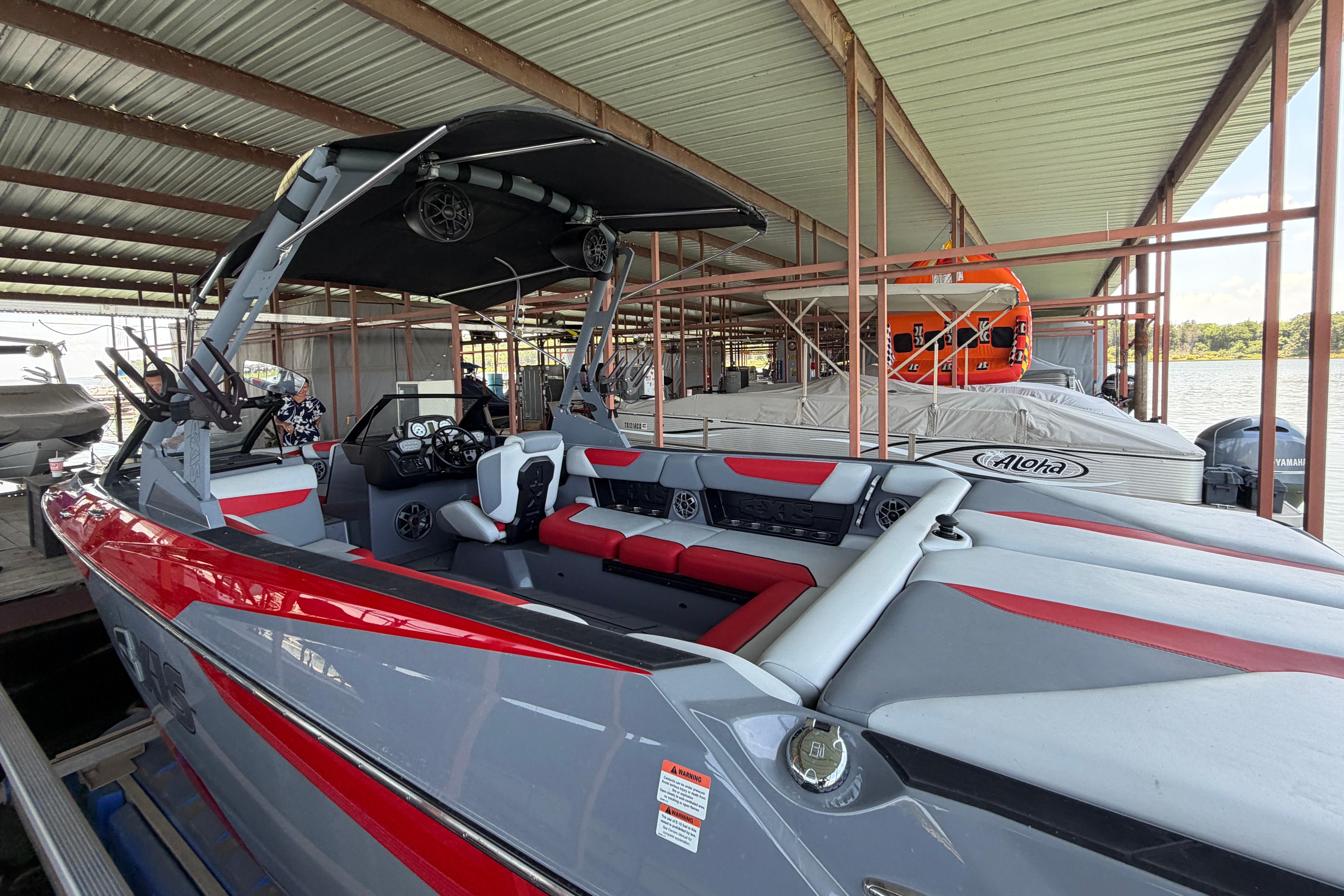 2021 Axis A24 boat with red and gray interior, docked under a covered marina.
