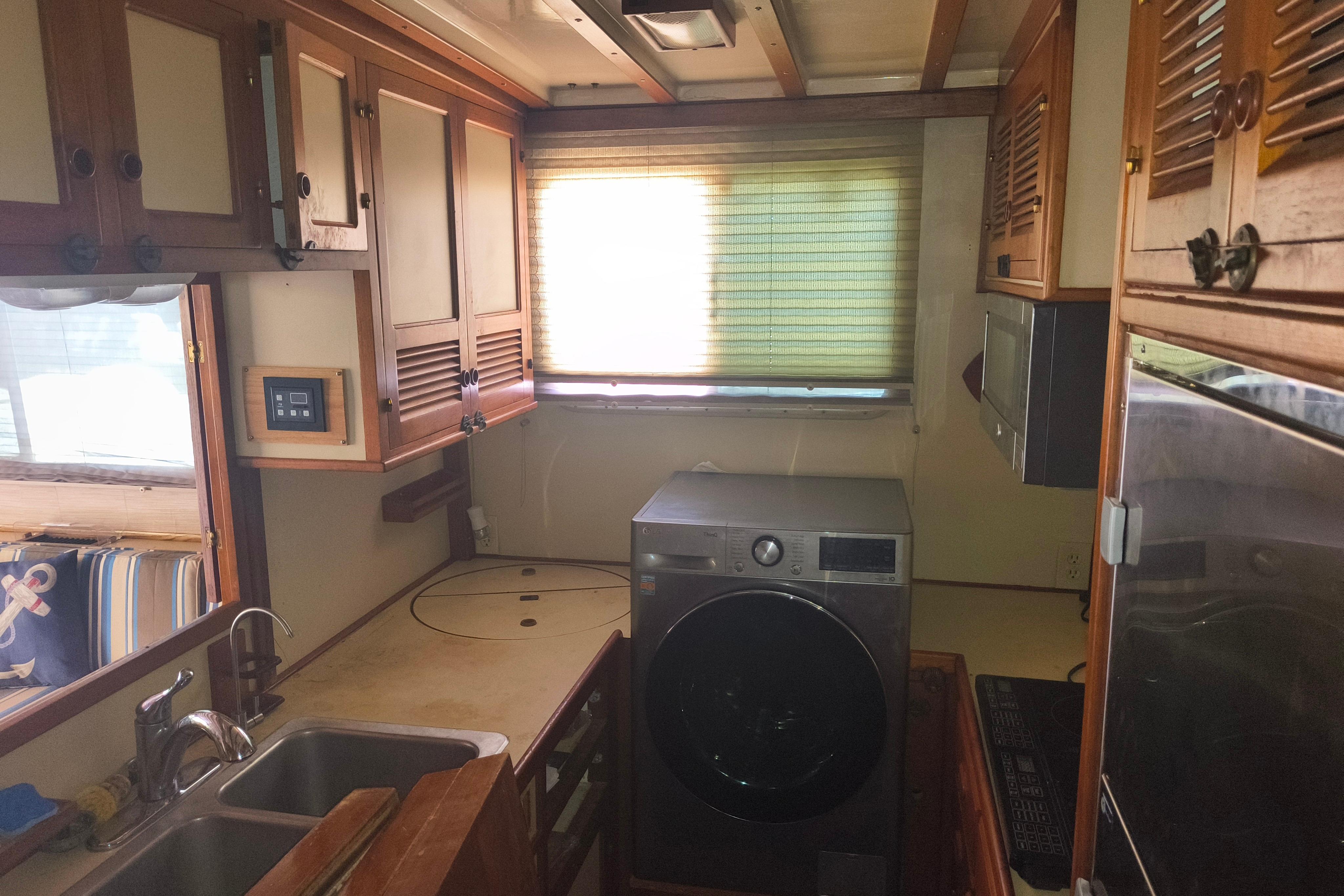 1984 Kadey-Krogen Manatee kitchen with wooden cabinets, sink, and washing machine.