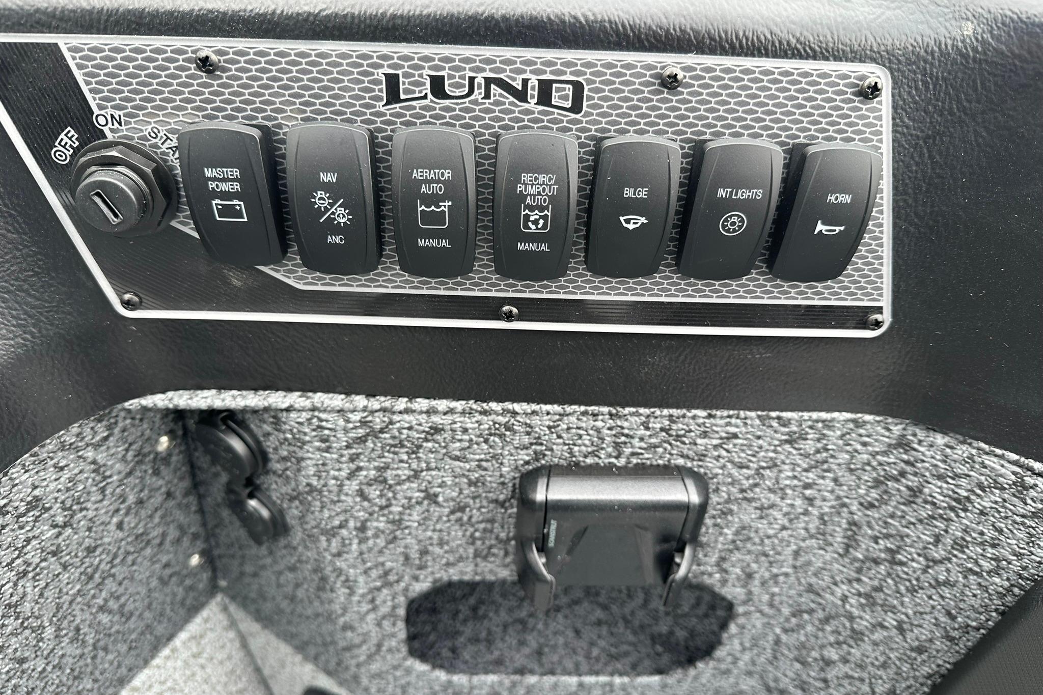 Control panel of 2026 Lund 1875 Impact XS SS boat with various switches.