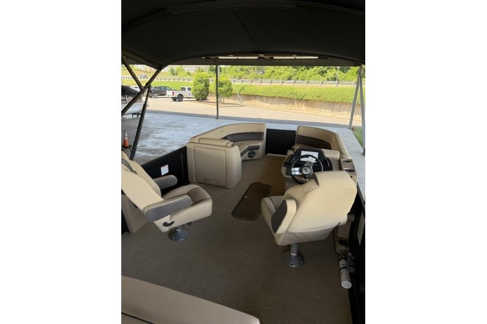 2025 Harris Sunliner 230 boat interior with beige seating and steering wheel.