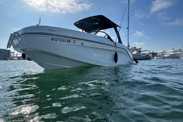 2024 Bayliner DX 2250 boat on water, sunny day, marina background.