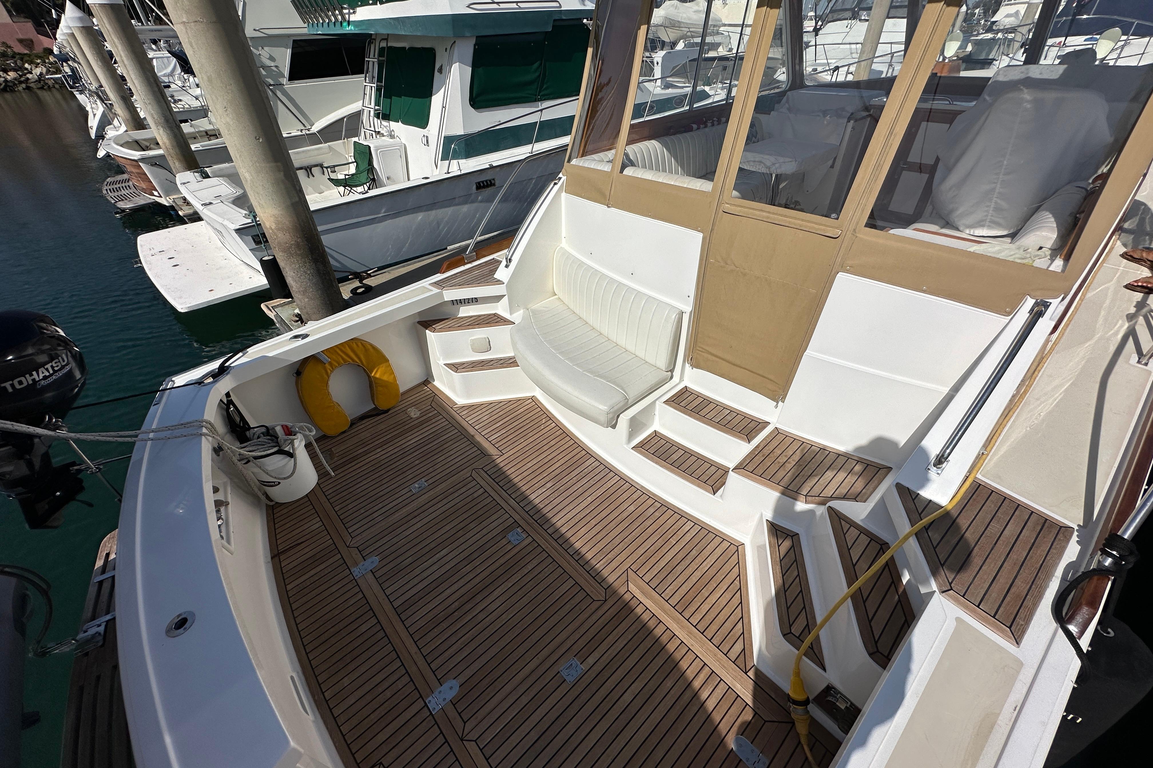 2003 Grand Banks 43 Eastbay HX yacht deck with seating and wooden flooring.