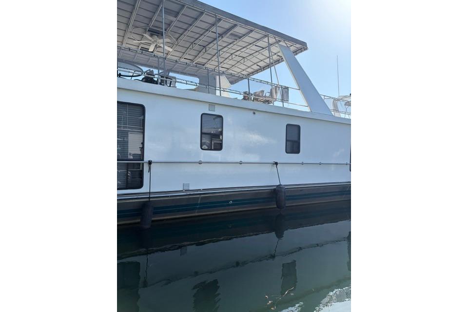 1997 Stardust Houseboat 18x83 on calm water, showcasing side view and upper deck.