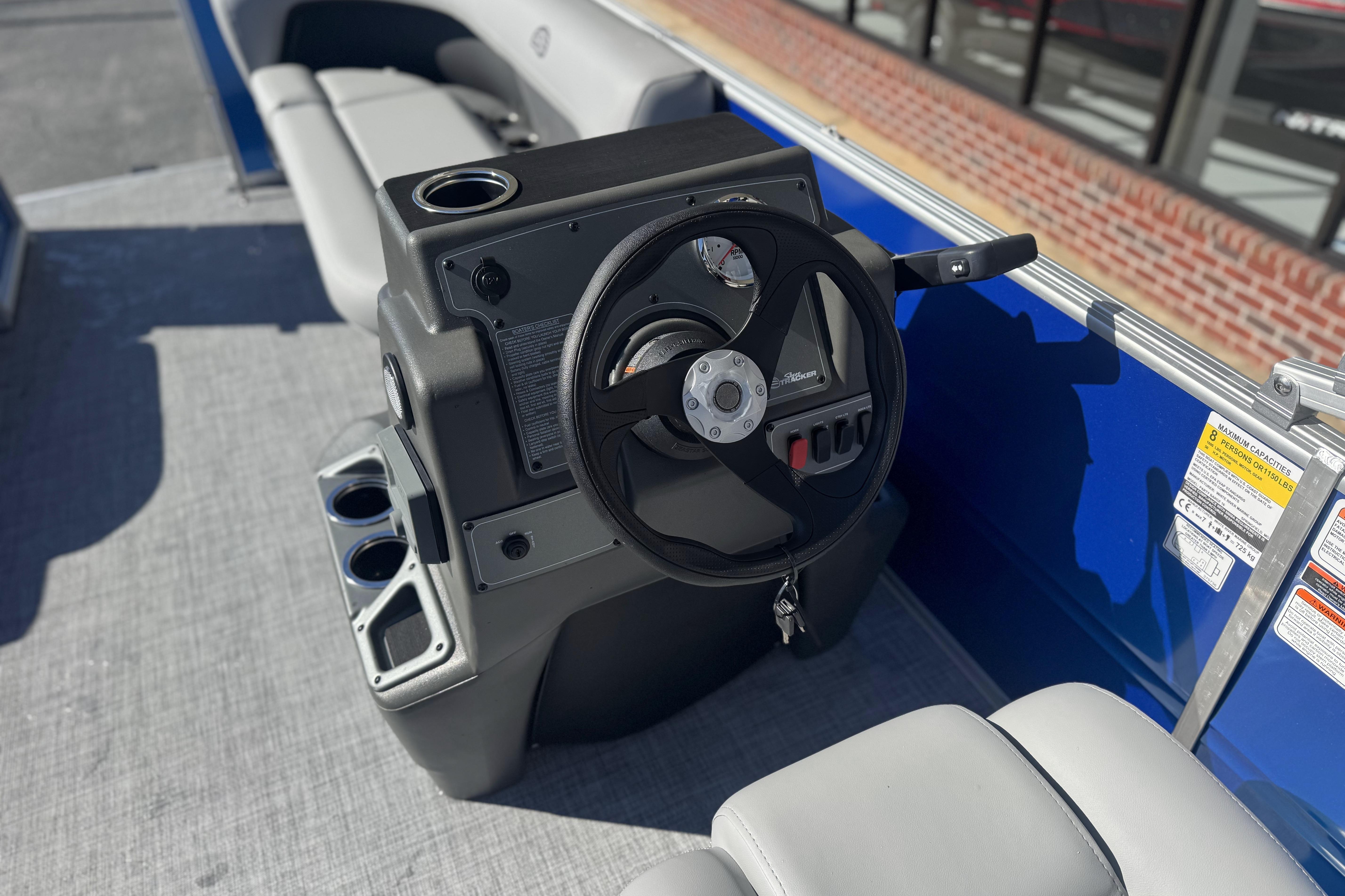 2026 Sun Tracker Party Barge 16 DLX steering console with cup holders and seating.