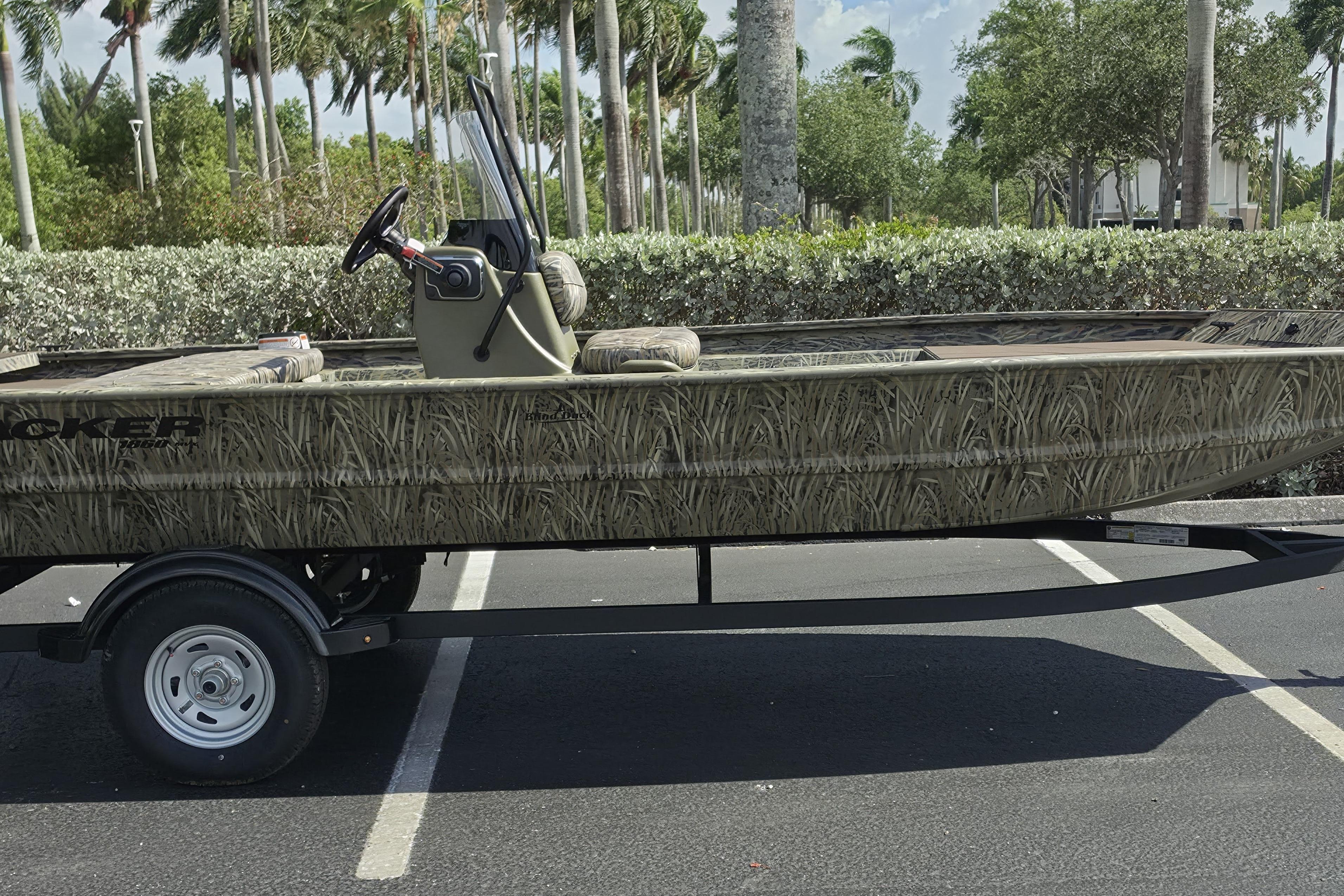 2026 Tracker Grizzly 1860 CC boat with camouflage design on a trailer in a parking lot.