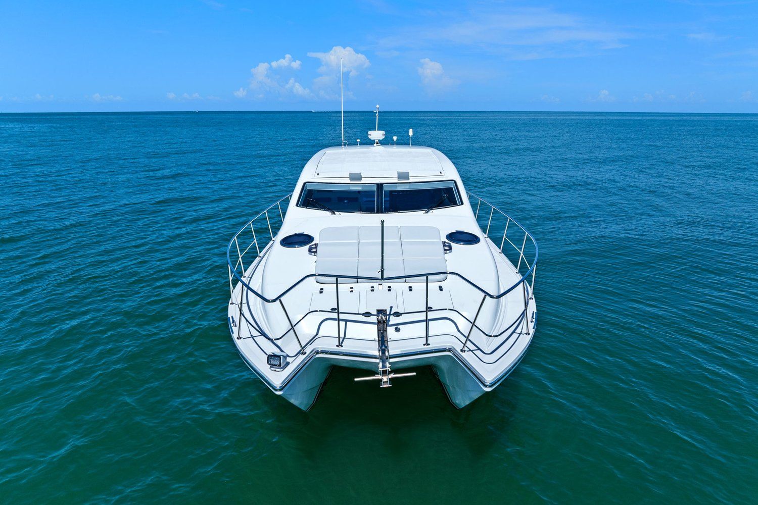 A white catamaran on calm, blue water under a clear sky.