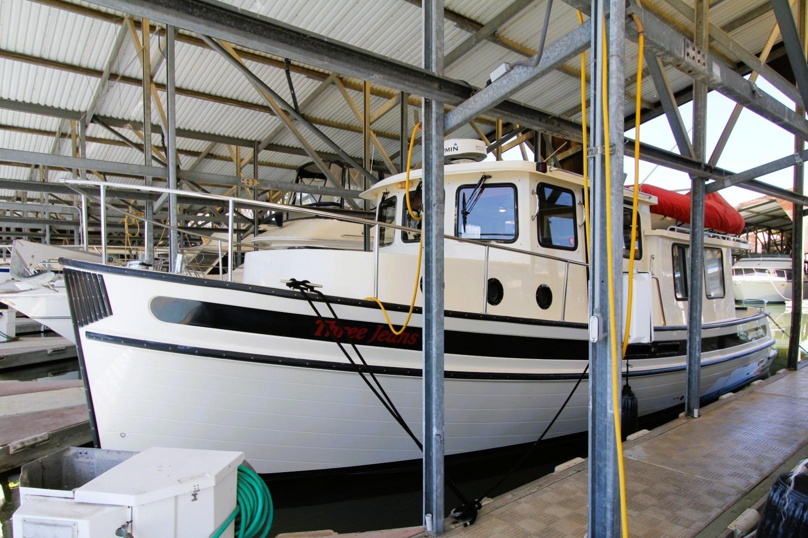 2002 Nordic Tug 37 docked in a covered marina, showcasing classic design and sturdy build.