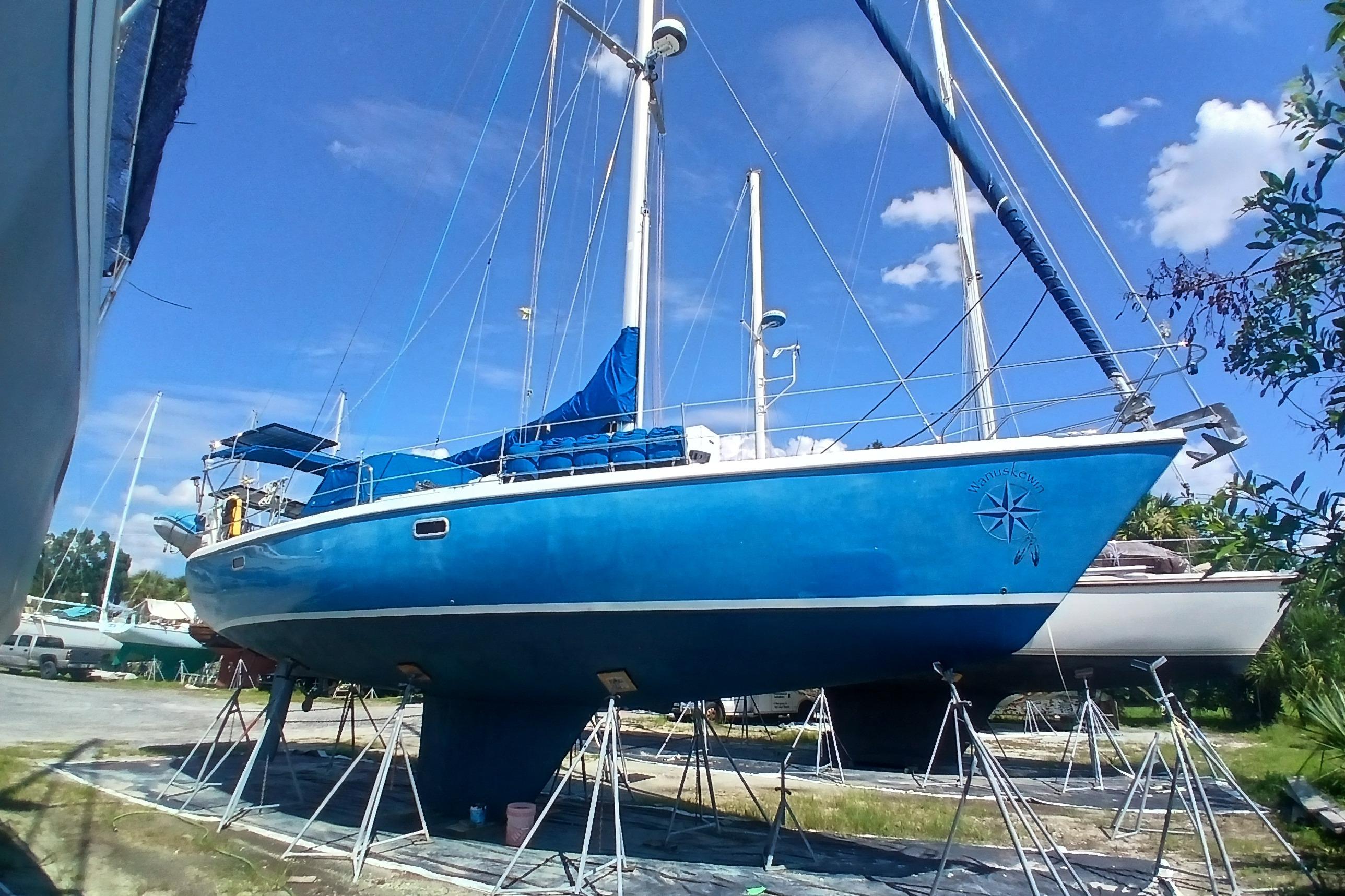 Blue 1995 Catalina 42 MkII sailboat on stands, clear sky background.