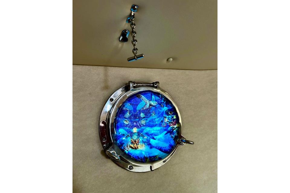 Porthole with vibrant blue ocean scene on a 2006 Nordic Tug 37 boat.