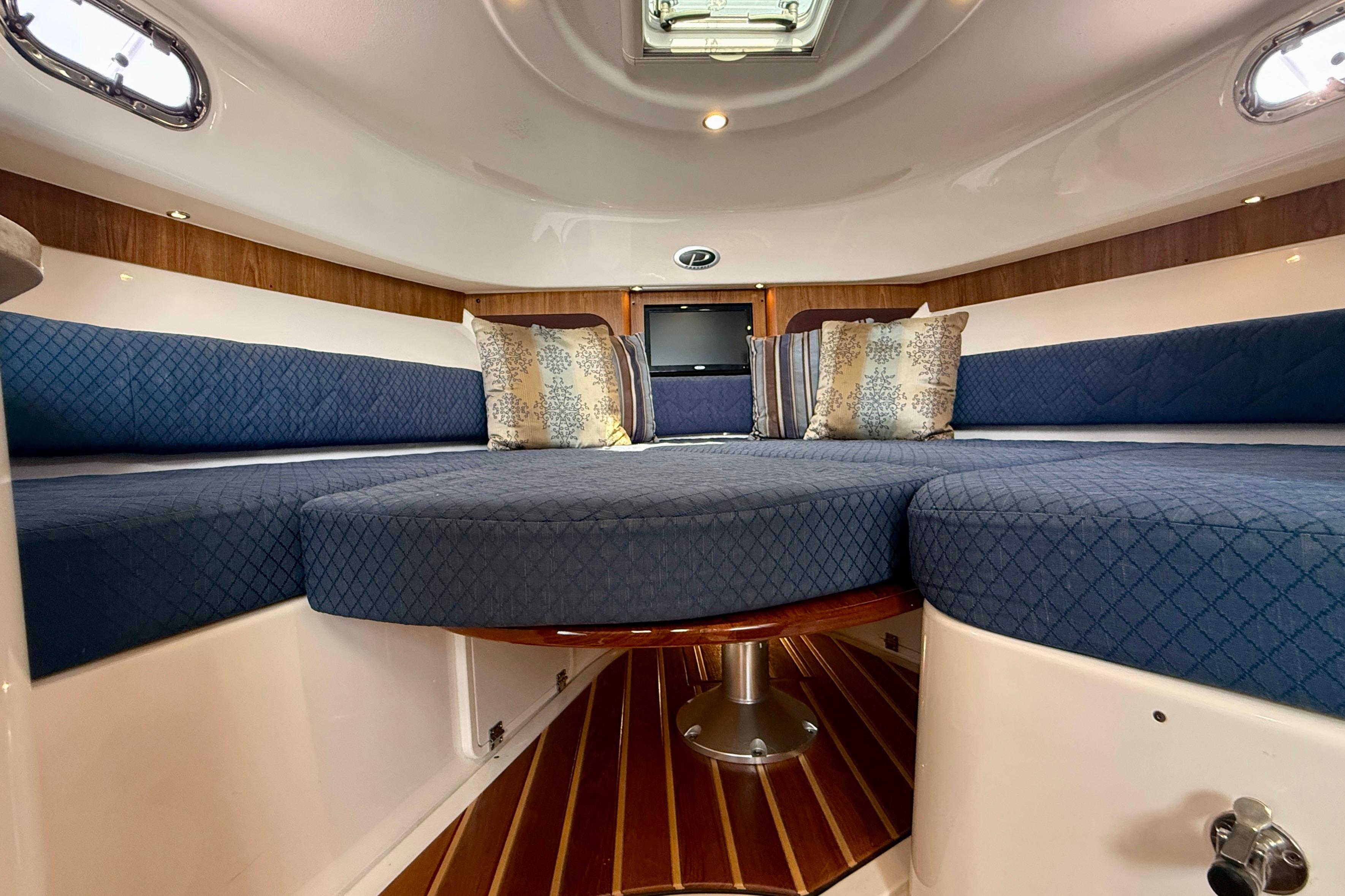 Interior of 2012 Pursuit OS 345 Offshore boat with blue seating and decorative pillows.