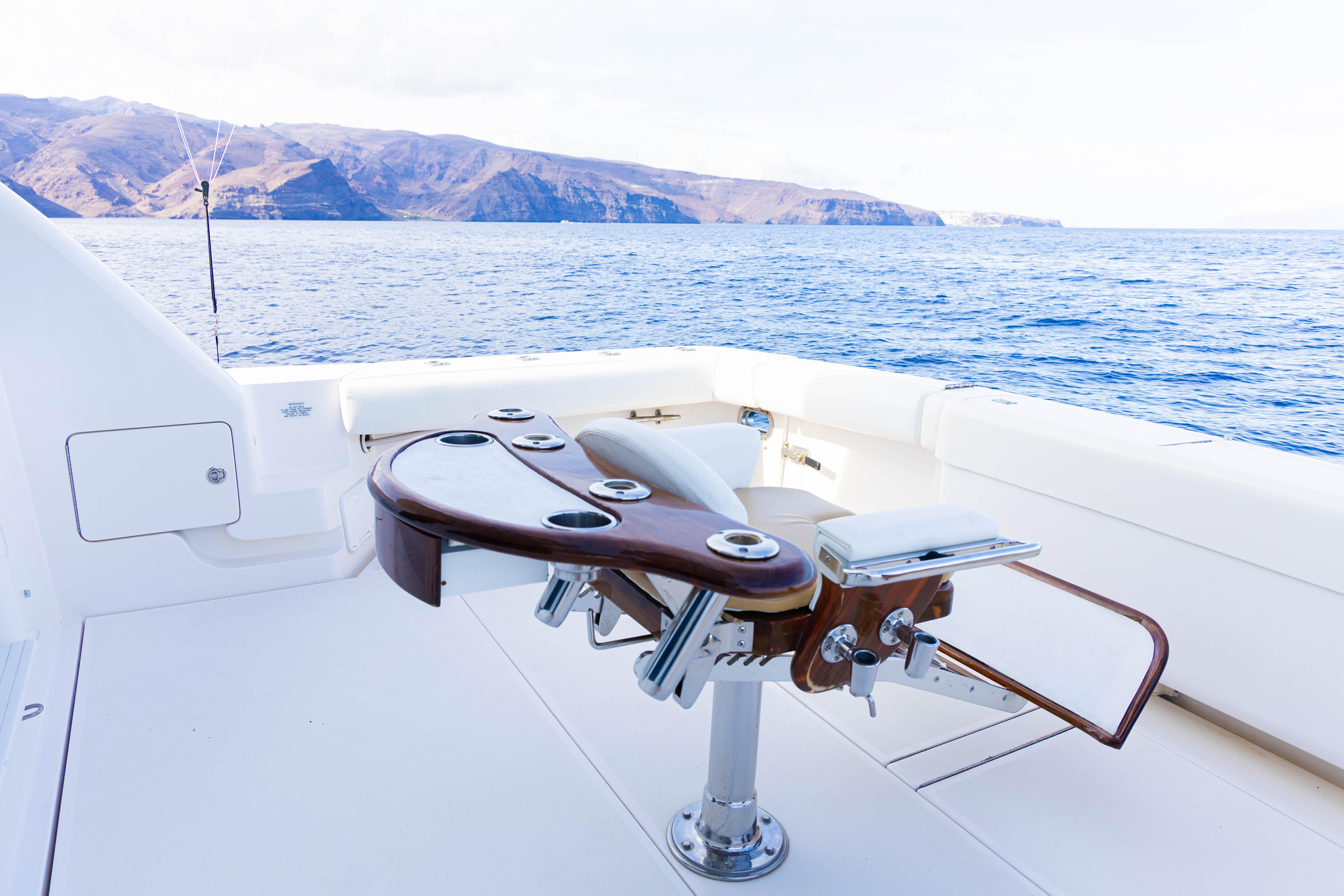 Luxury Bertram 510 yacht deck with fishing chair, ocean view, and distant mountains, 2006 model.