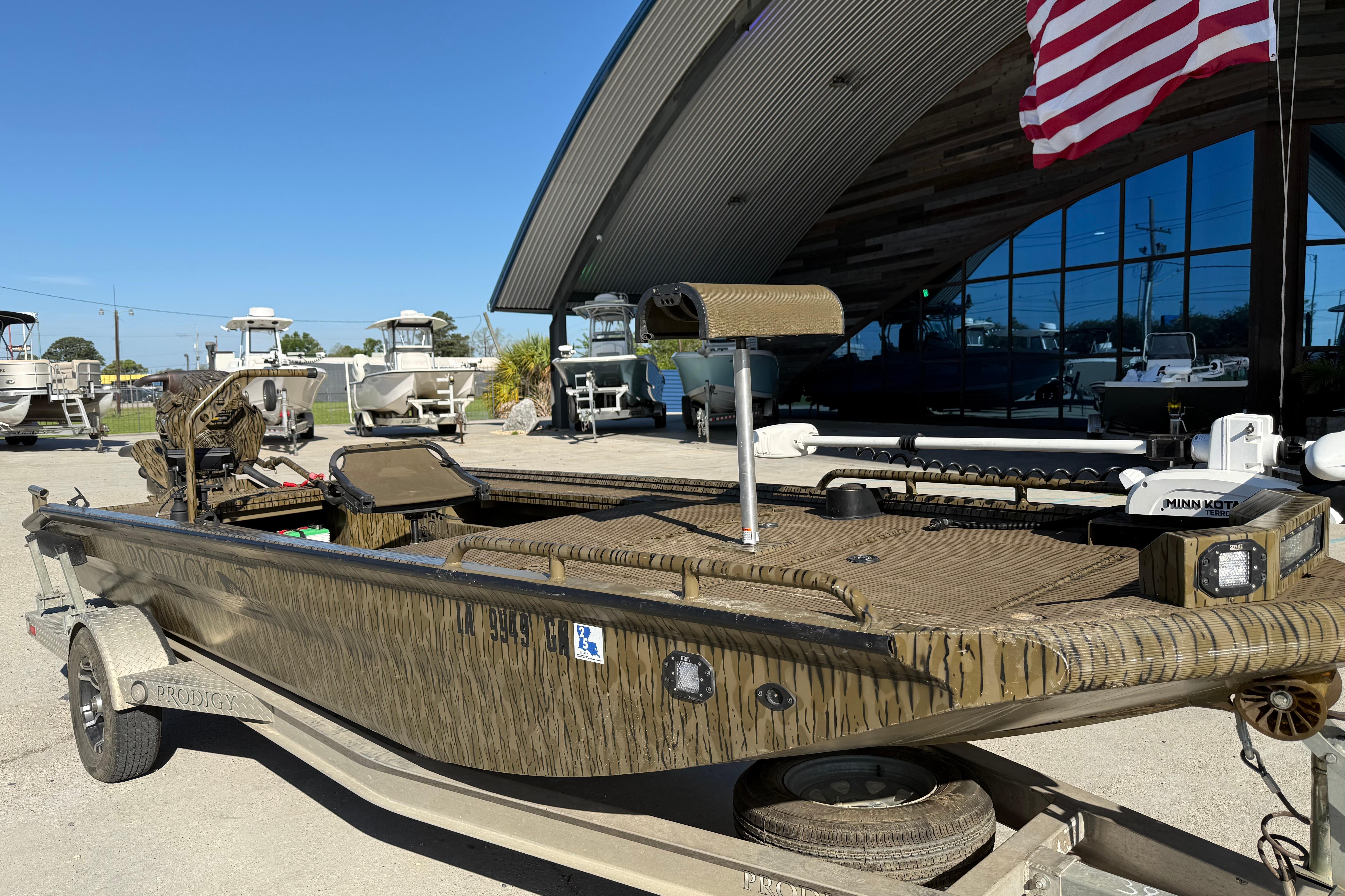 2022 Prodigy 1854 boat on trailer, parked outdoors with American flag in background.