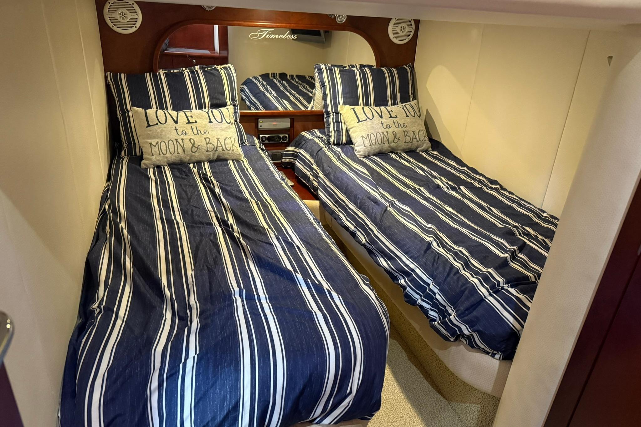 Twin beds with striped bedding in 2005 Chris-Craft Roamer 40 cabin, featuring decorative pillows.