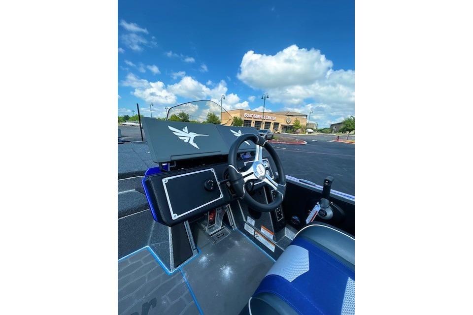 2026 Ranger Z521 boat cockpit with steering wheel, dashboard, and blue seating under a clear sky.