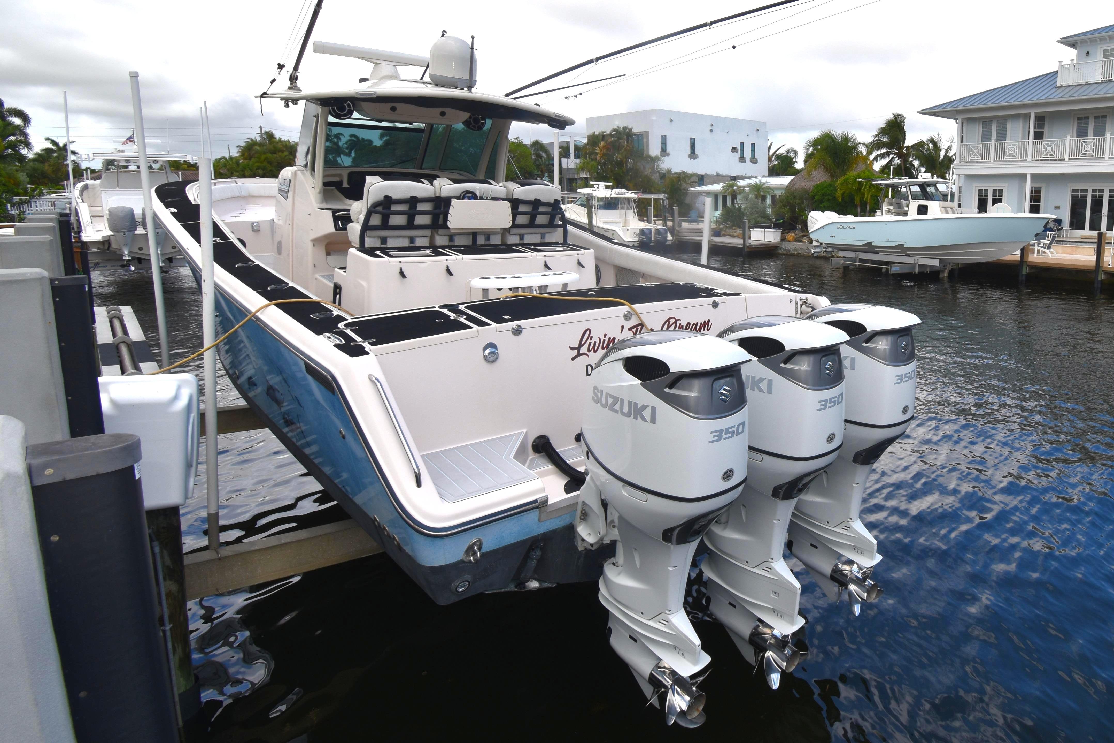 2010 Grady-White Canyon 366 boat docked by waterfront home, featuring triple Suzuki engines.