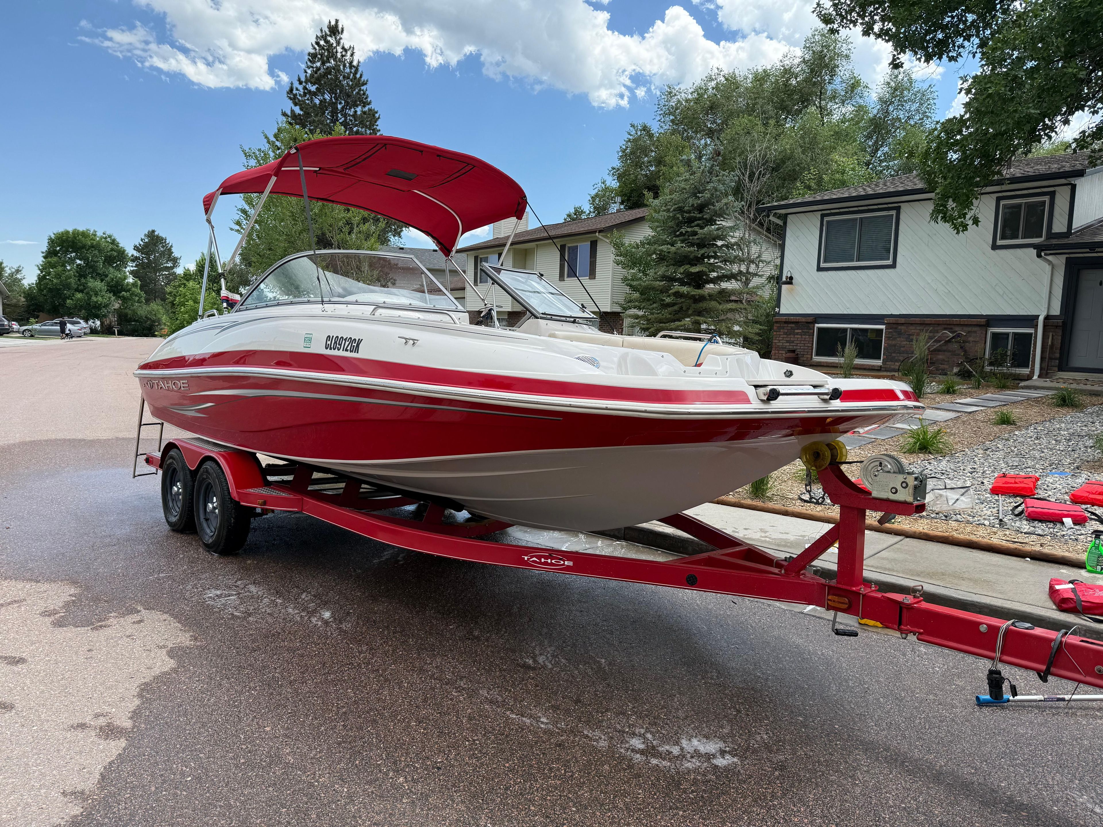Red 2011 Tahoe 216 WT boat on trailer in residential area.