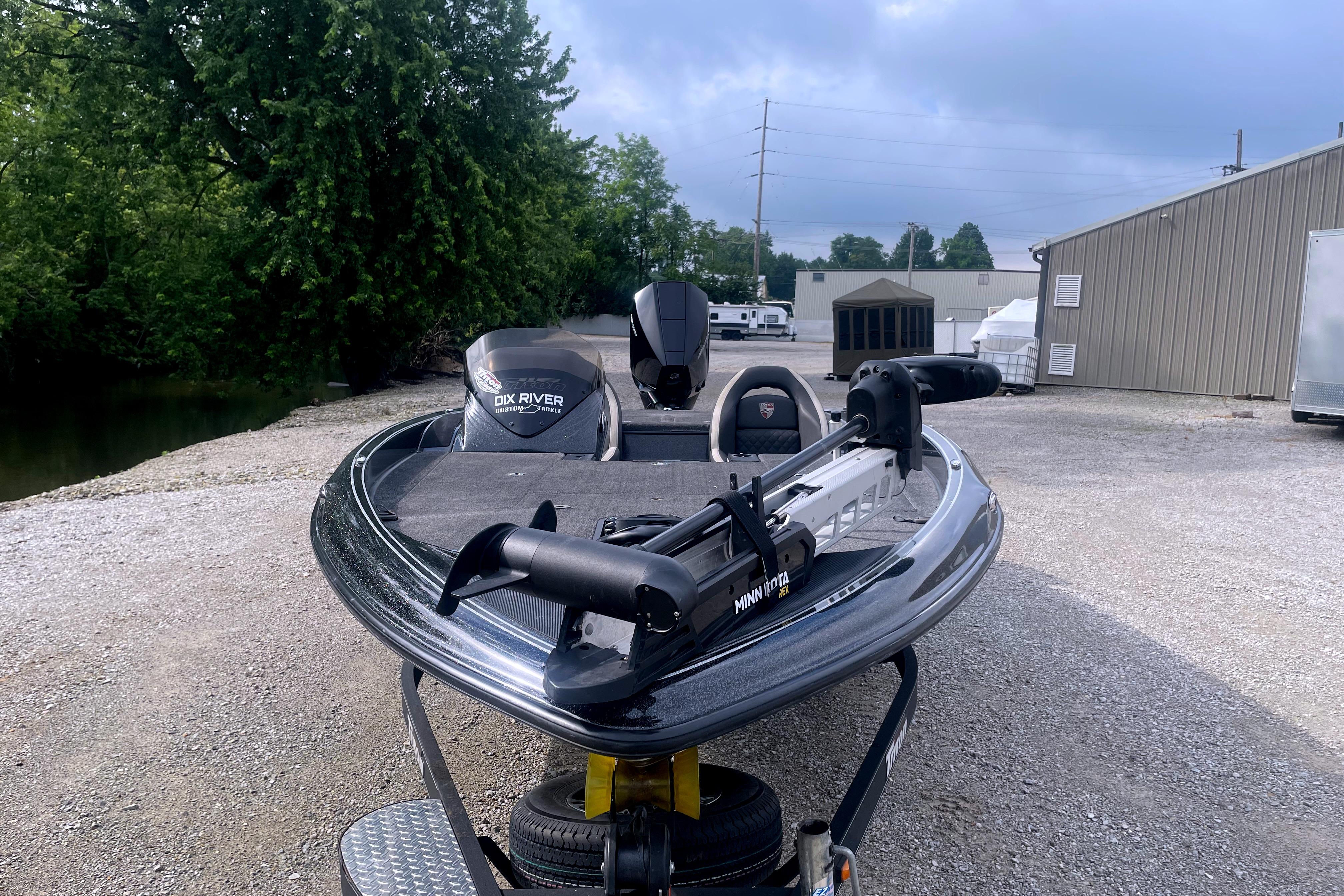 2022 Triton 18 TrX boat with Minn Kota trolling motor, parked outdoors near trees and buildings.