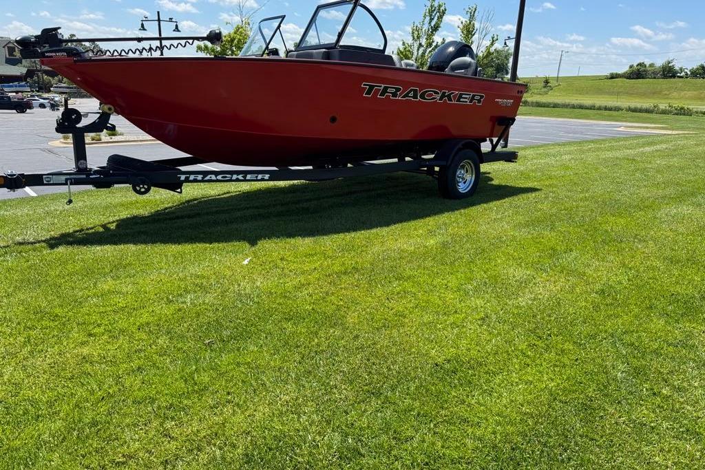 Red 2026 Tracker Pro Guide V-16 WT boat on trailer, parked on grass.