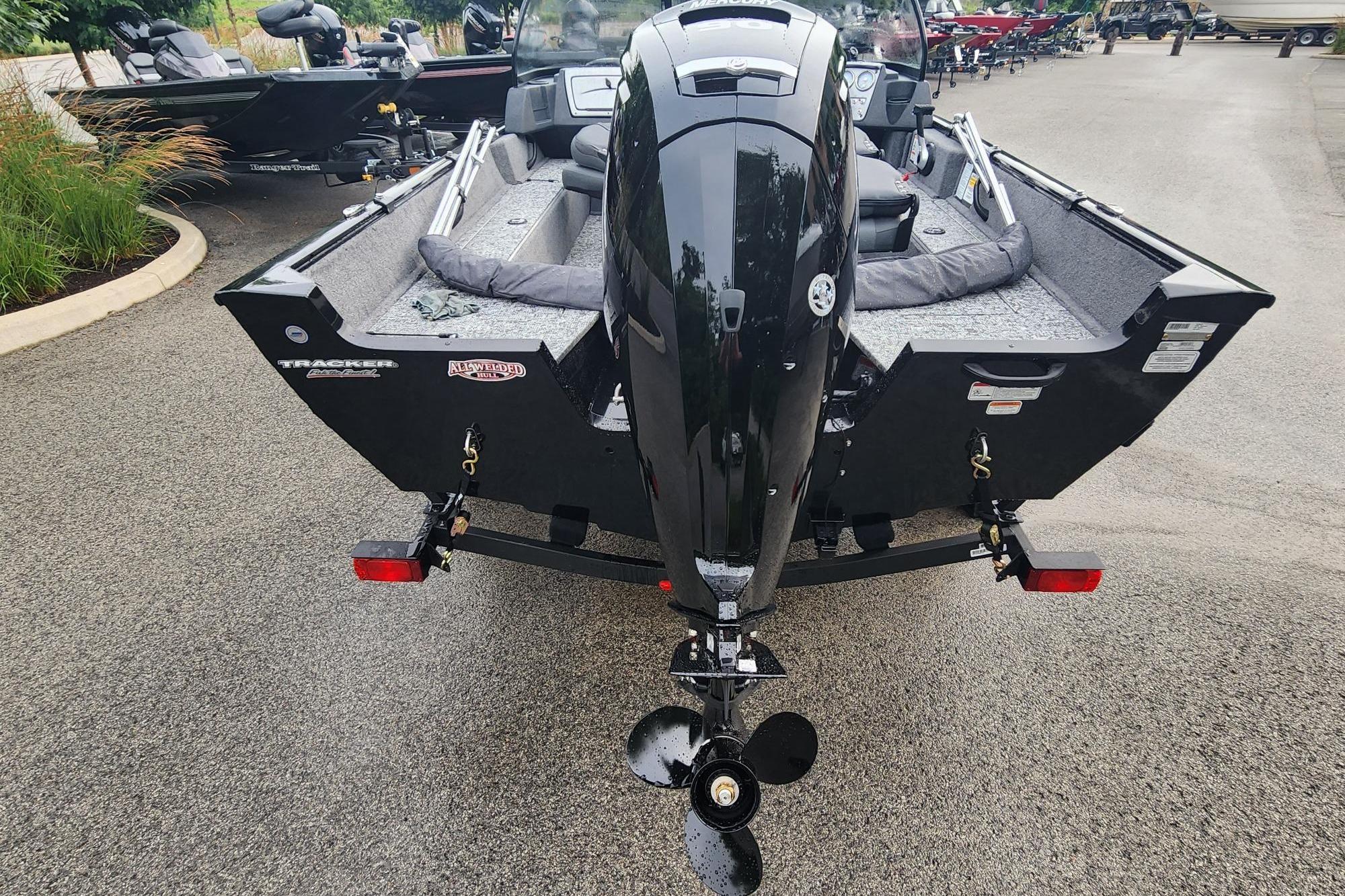 2026 Tracker Pro Guide V-16 WT boat, rear view with motor, parked on pavement.