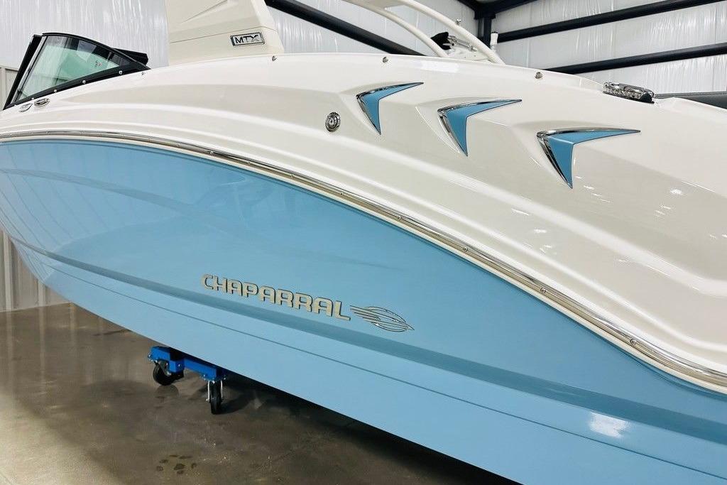 2025 Chaparral 23 SSi OB boat with sleek blue and white design in showroom.