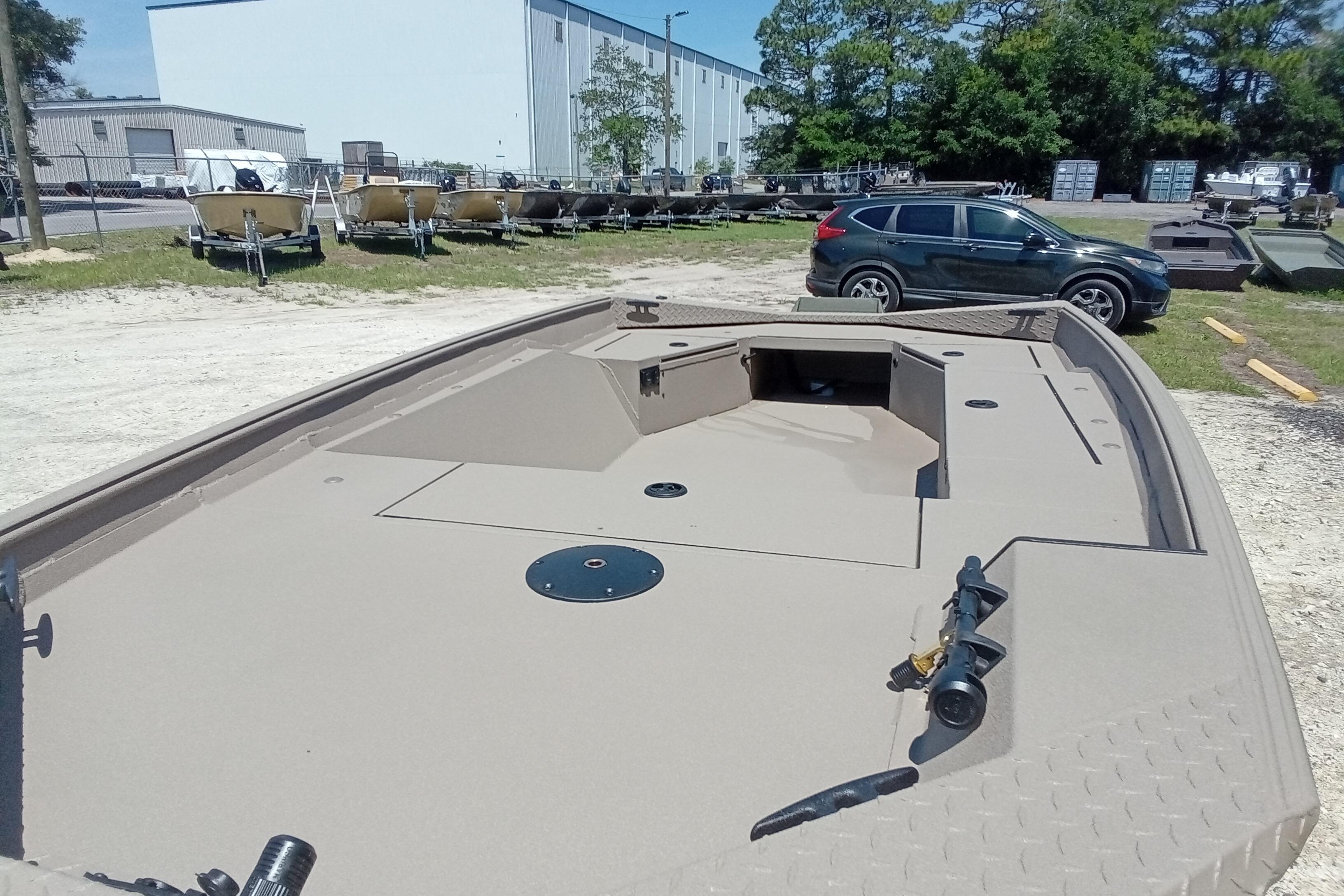 2026 Alweld 1652 Invader boat in outdoor showroom, beige deck, parked cars nearby.