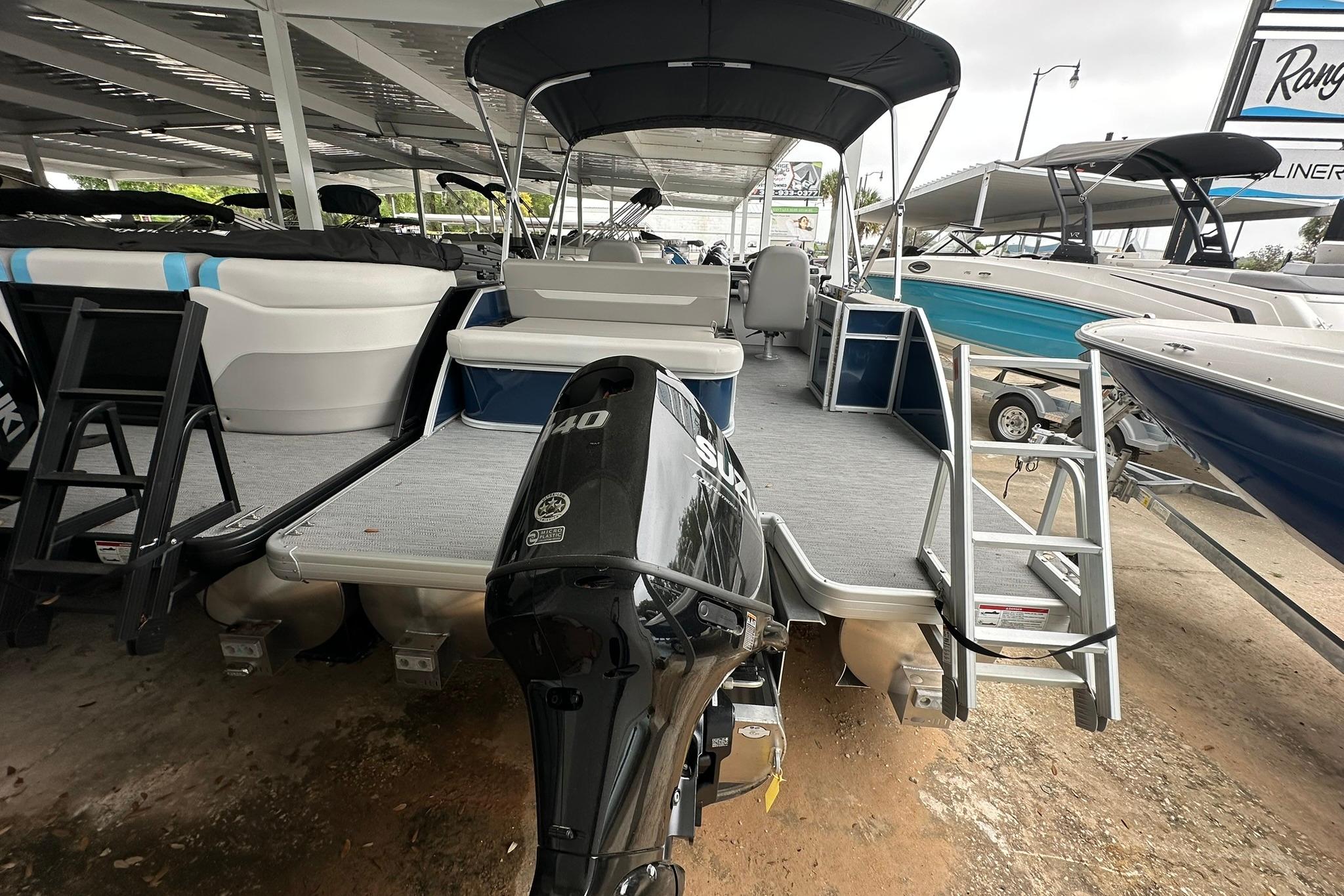 2026 Sweetwater EX 2286 SFLX pontoon boat with Suzuki outboard motor in a showroom.