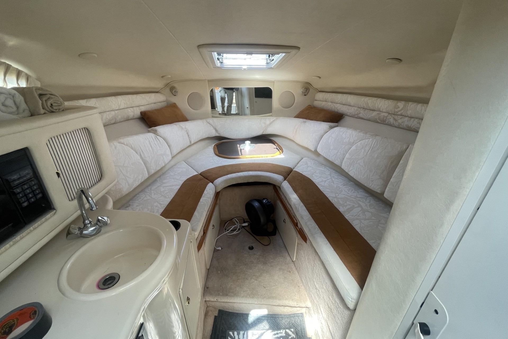 Interior of 2000 Sea Ray Sundancer 260 boat with cozy seating and kitchenette.