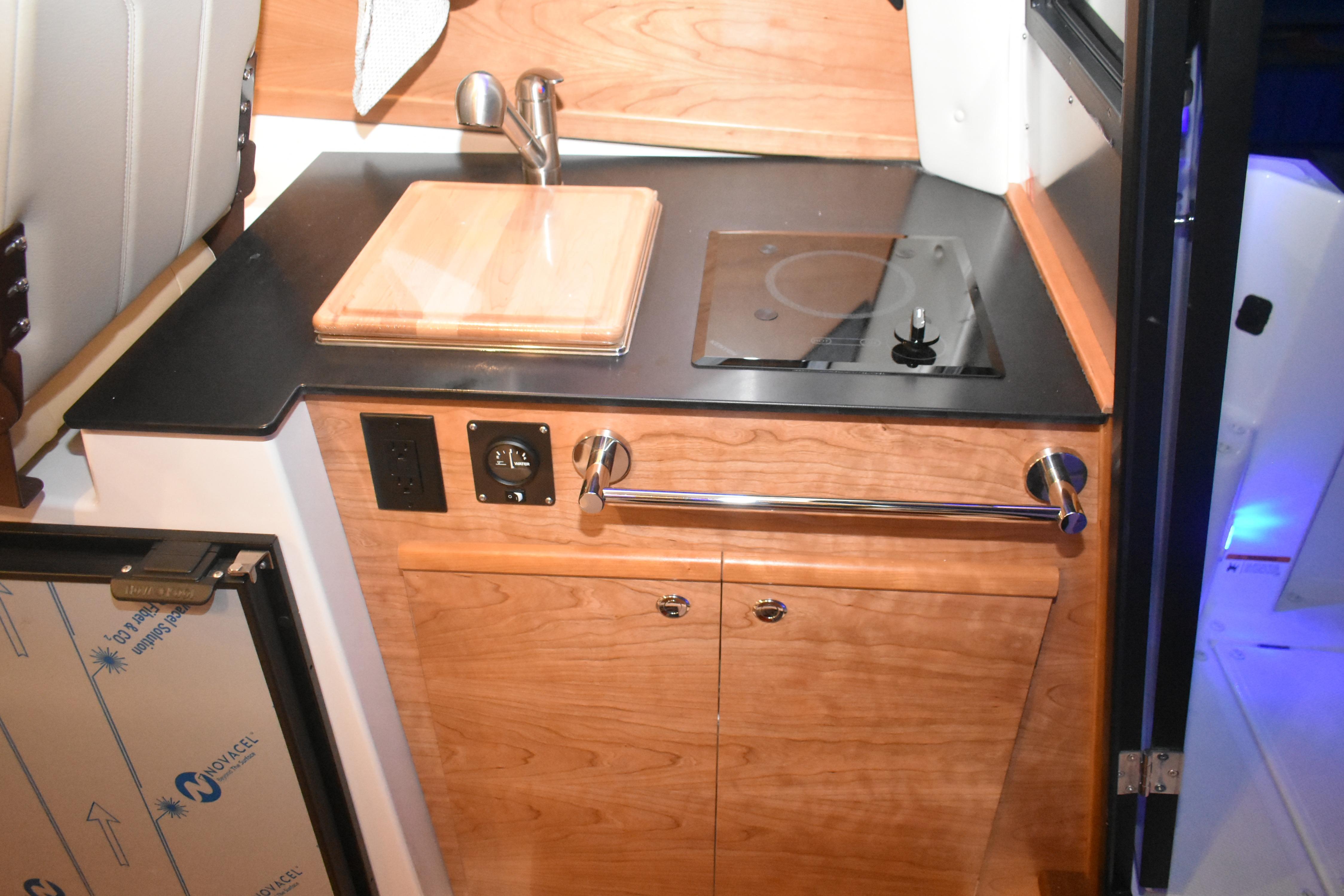 2026 Cutwater C-248 Coupe interior kitchen with sink, stove, and wooden cabinetry.