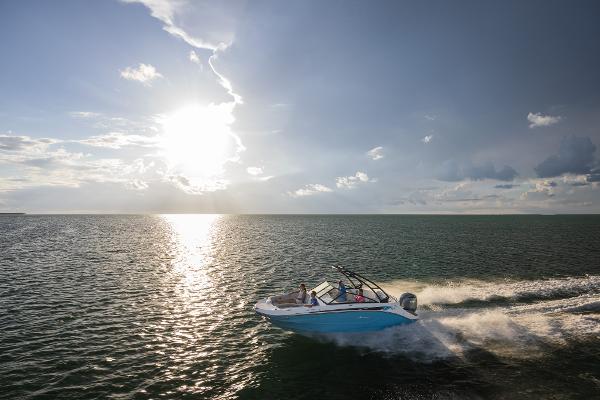 2025 Hurricane SunDeck 235 OB cruising on open water at sunset.