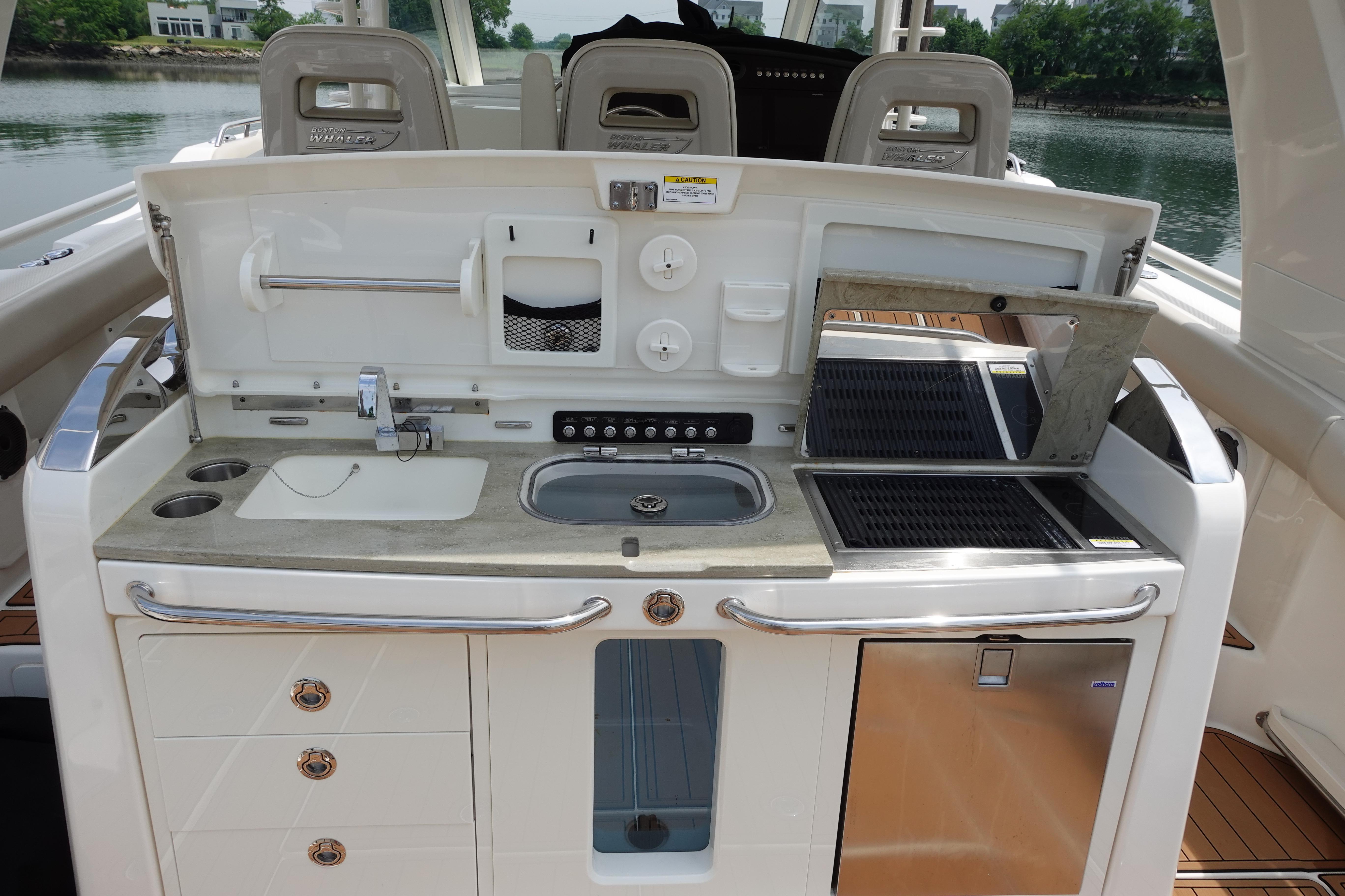 2020 Boston Whaler 420 Outrage boat kitchen with sink, grill, and storage drawers.