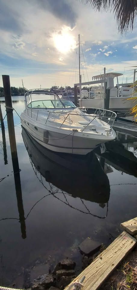A 2002 Wellcraft 3300 Martinique is docked in the water on a sunny day at the marina.