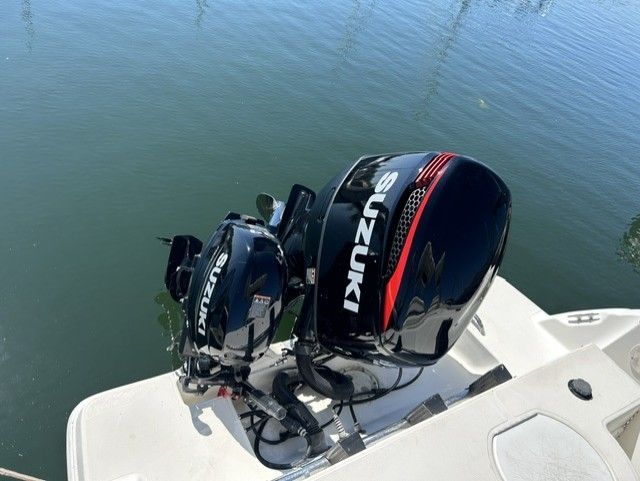 Two Suzuki outboard motors on a boat in calm water.
