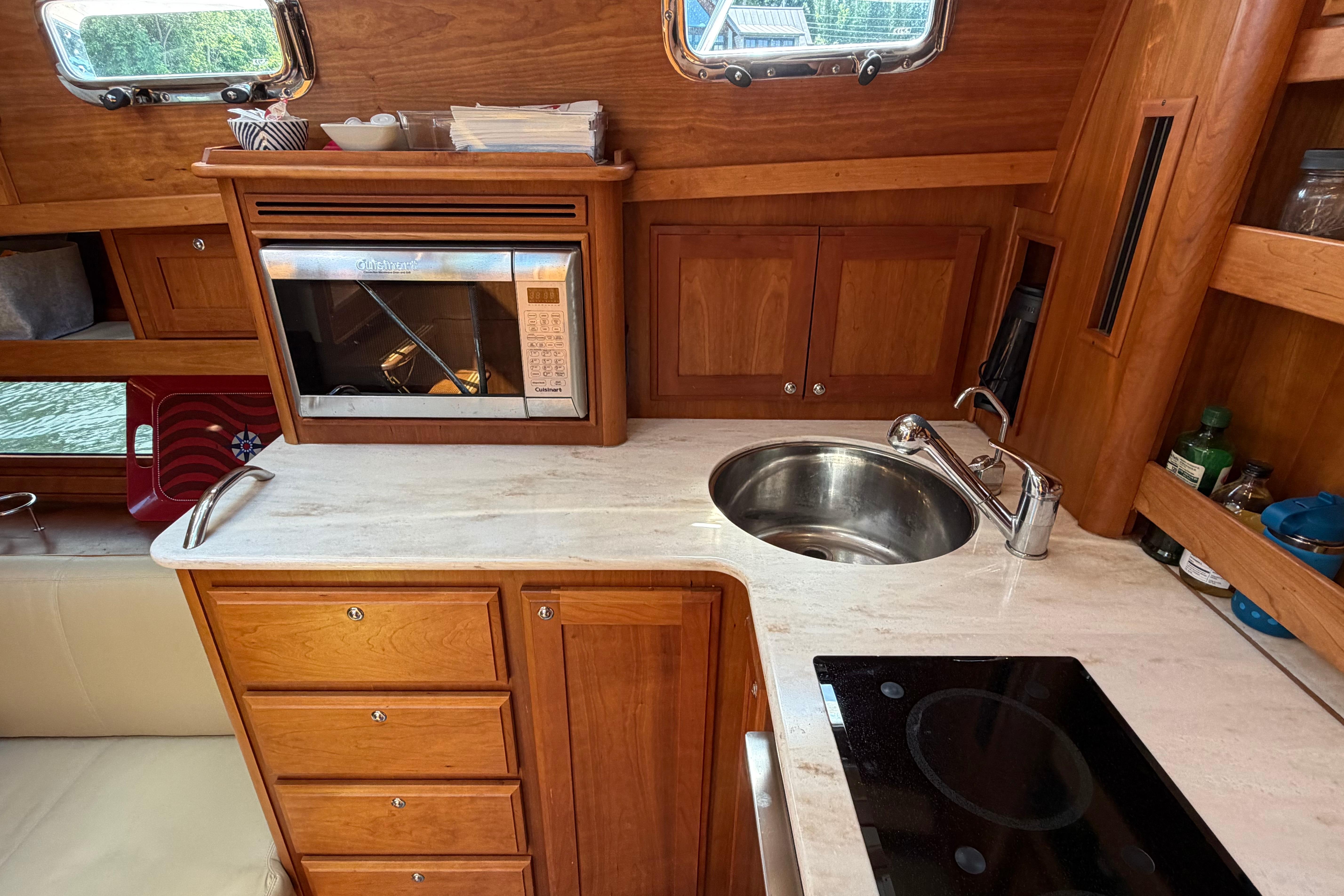 2015 Sabre 38 Salon Express galley with wood cabinetry, sink, microwave, and stovetop.