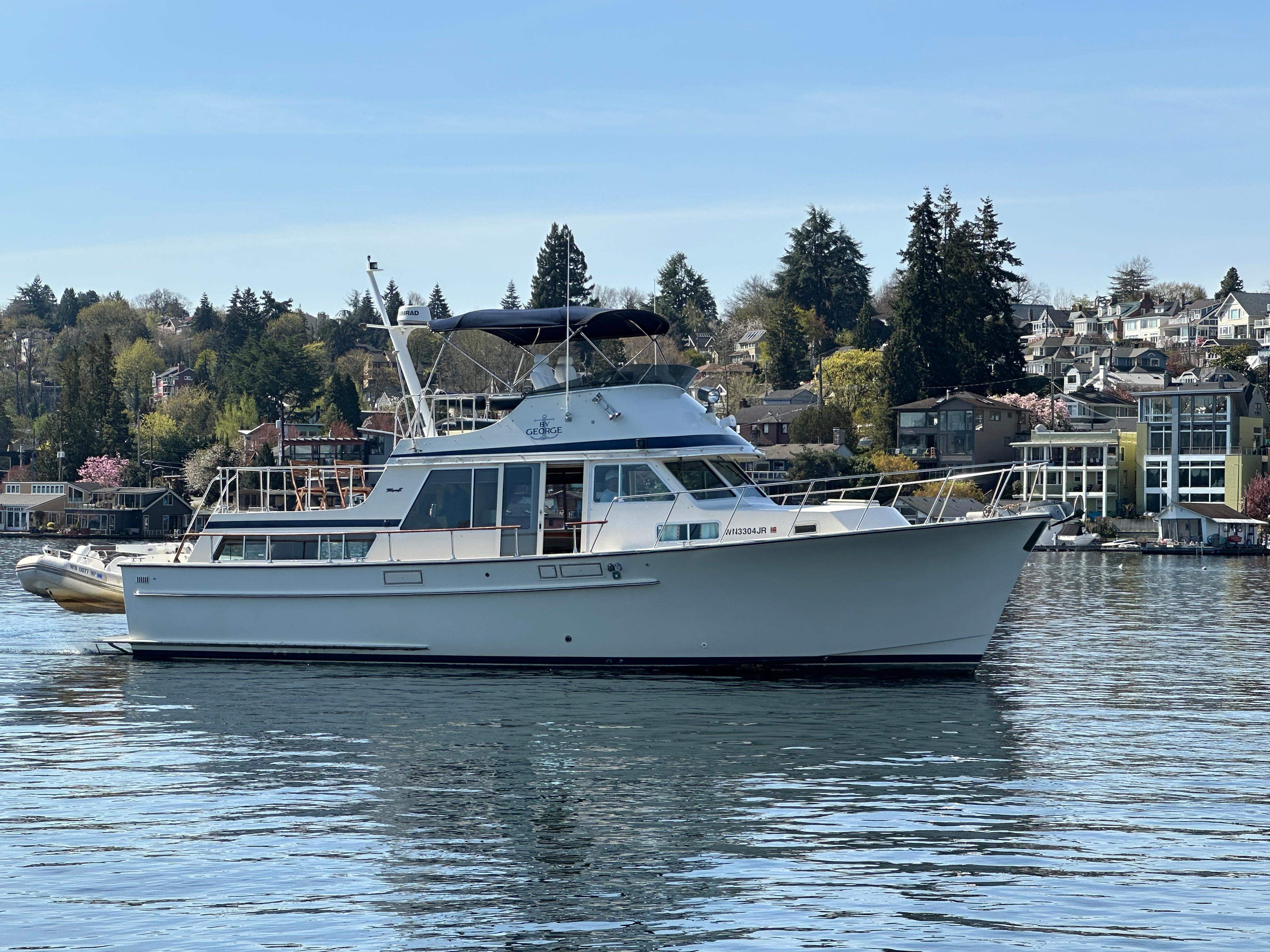 1982 Tollycraft Tri Cabin yacht on calm water with scenic shoreline background.