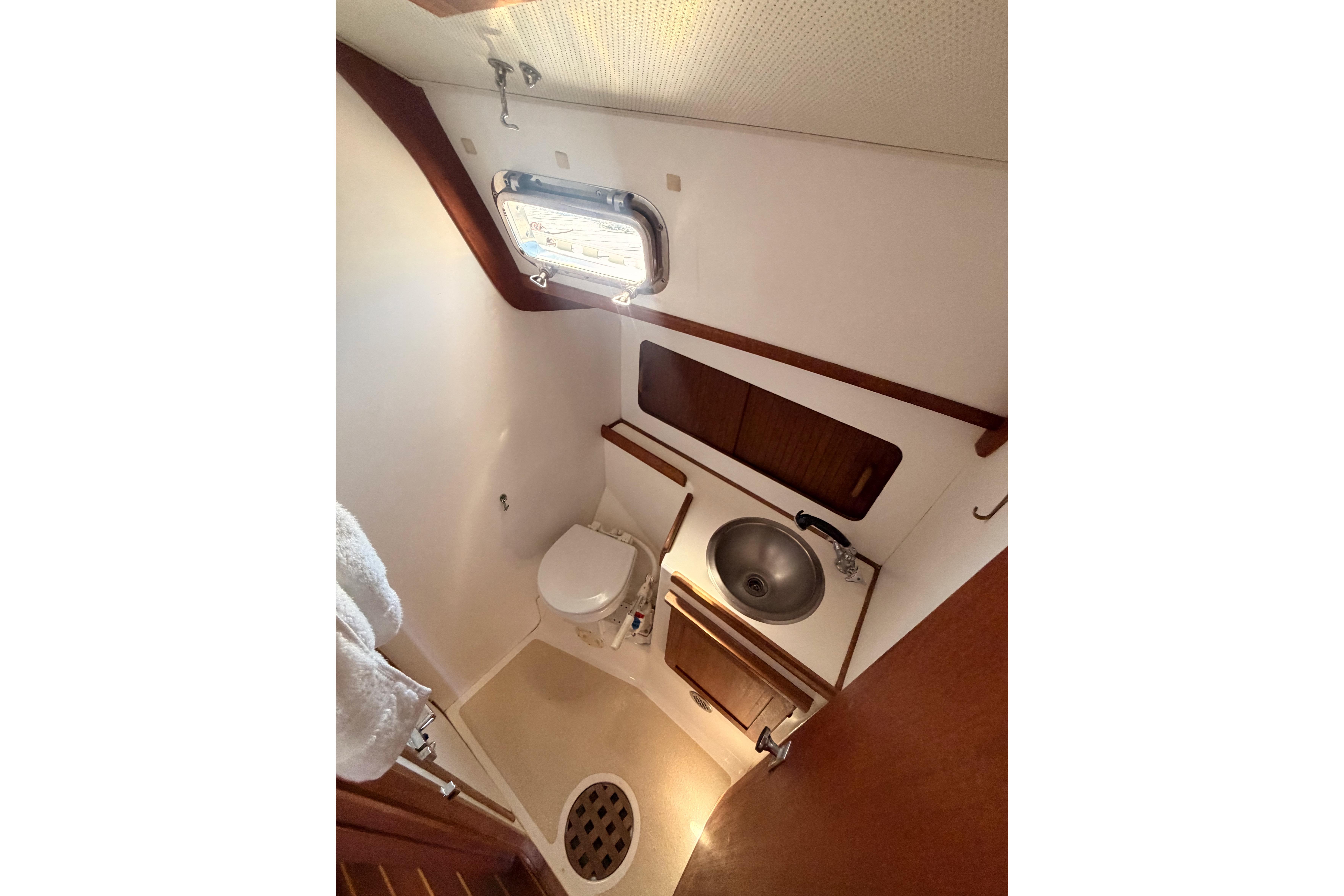 1991 Caliber 33 yacht bathroom with toilet, sink, and porthole window.