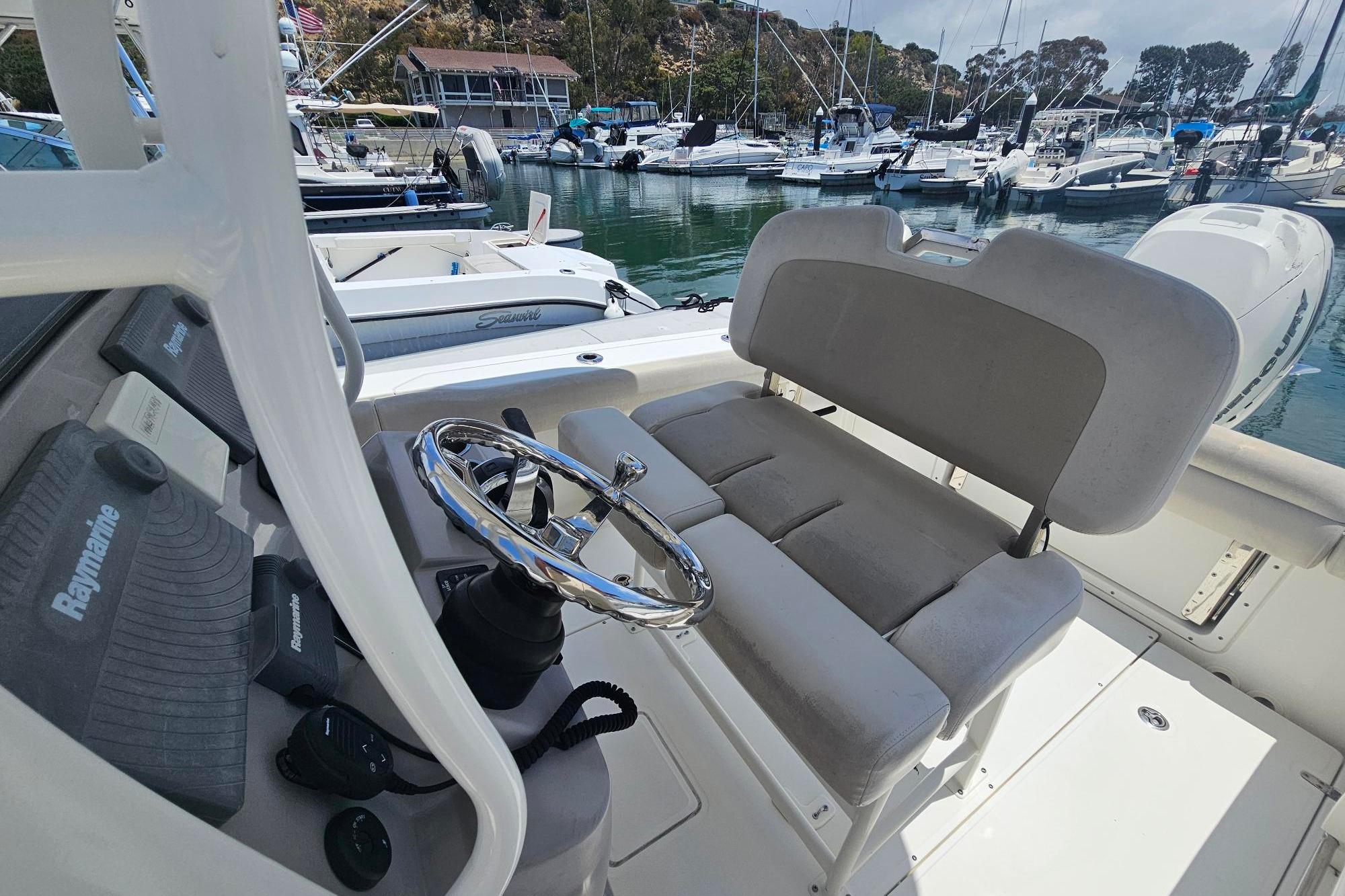 2017 Boston Whaler 230 Outrage boat interior with steering wheel and seating, docked in marina.