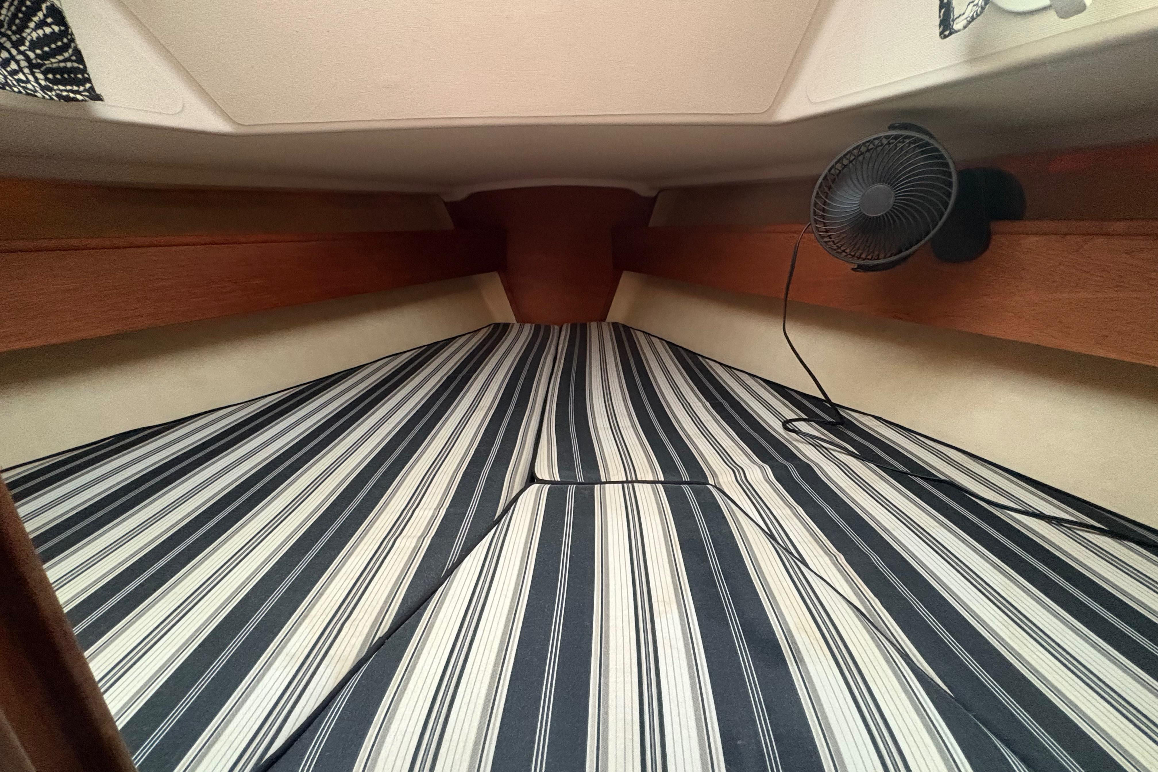 Interior of 1981 Sabre 31 sailboat with striped bedding and small fan.