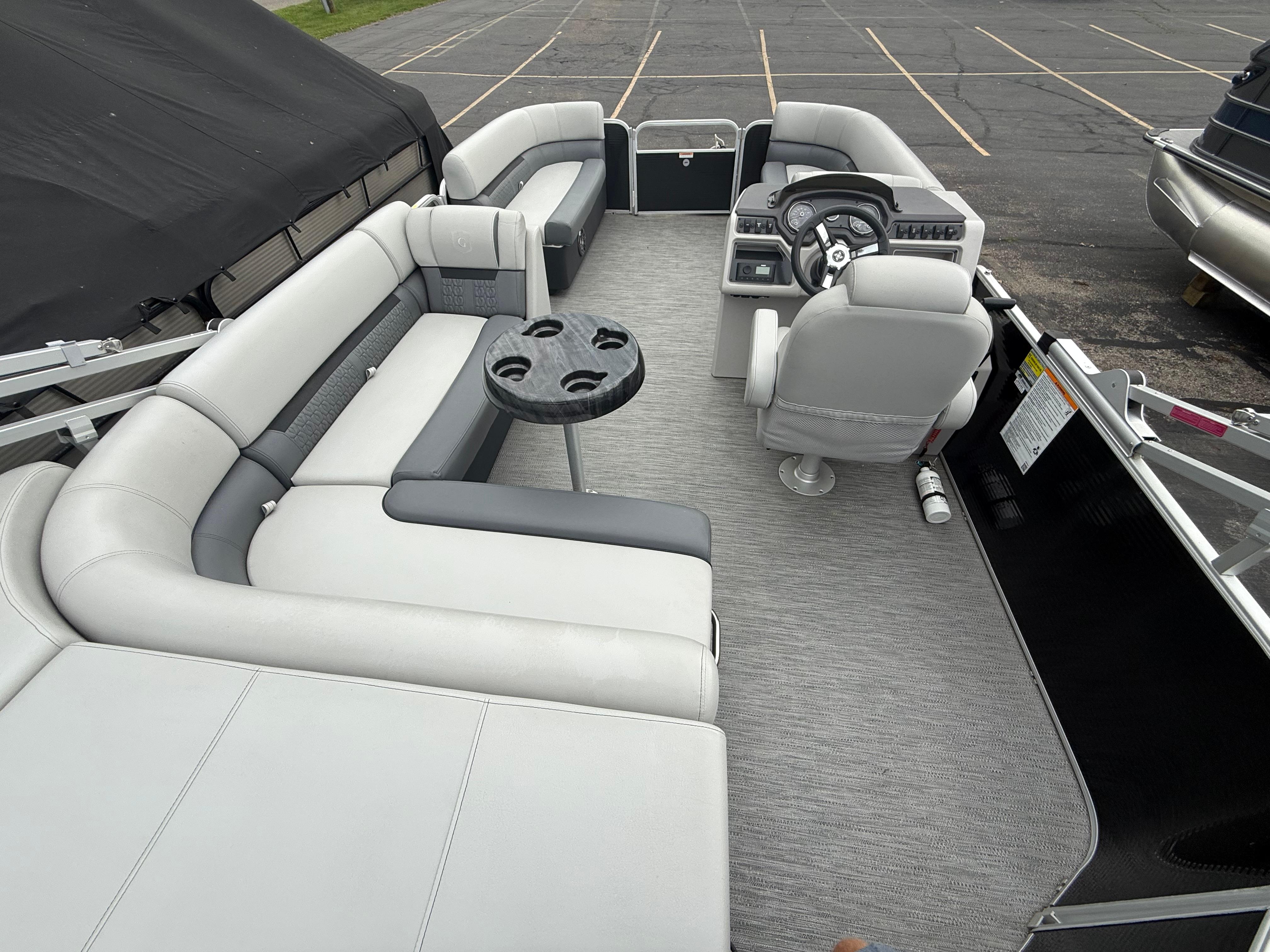 Interior of a 2023 Godfrey Sweetwater pontoon boat with gray seating and steering console.