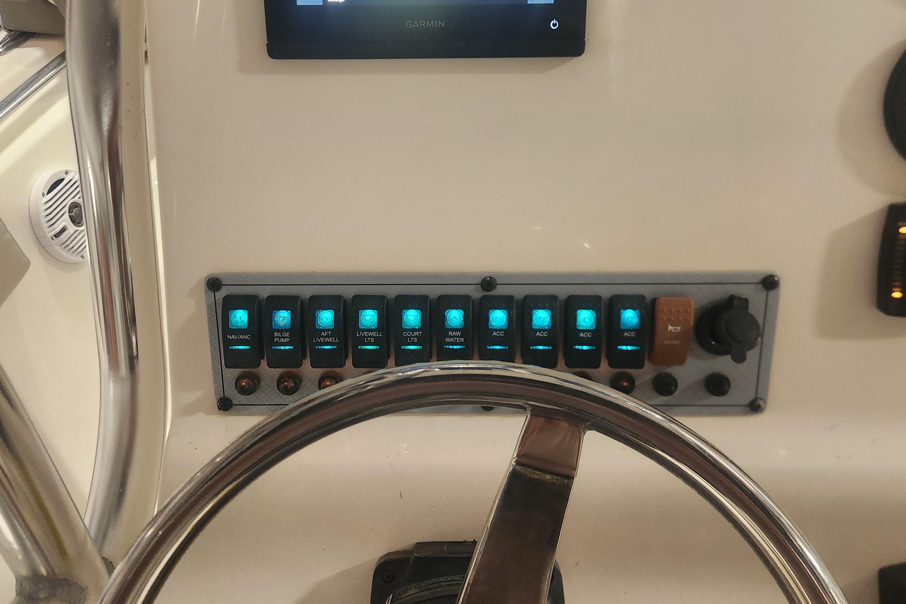 Control panel of 2023 Key West 219 FS boat with illuminated switches and steering wheel.